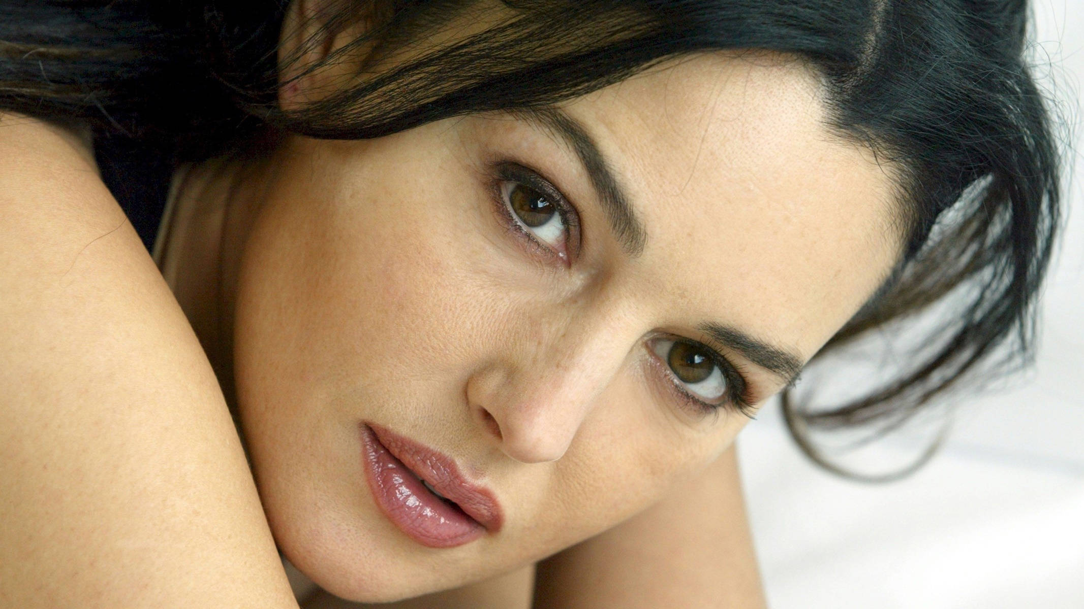 monica bellucci 桌布 壁紙 — 一位深色頭髮、棕色眼睛的女性特寫肖像，以柔和的表情直視鏡頭。