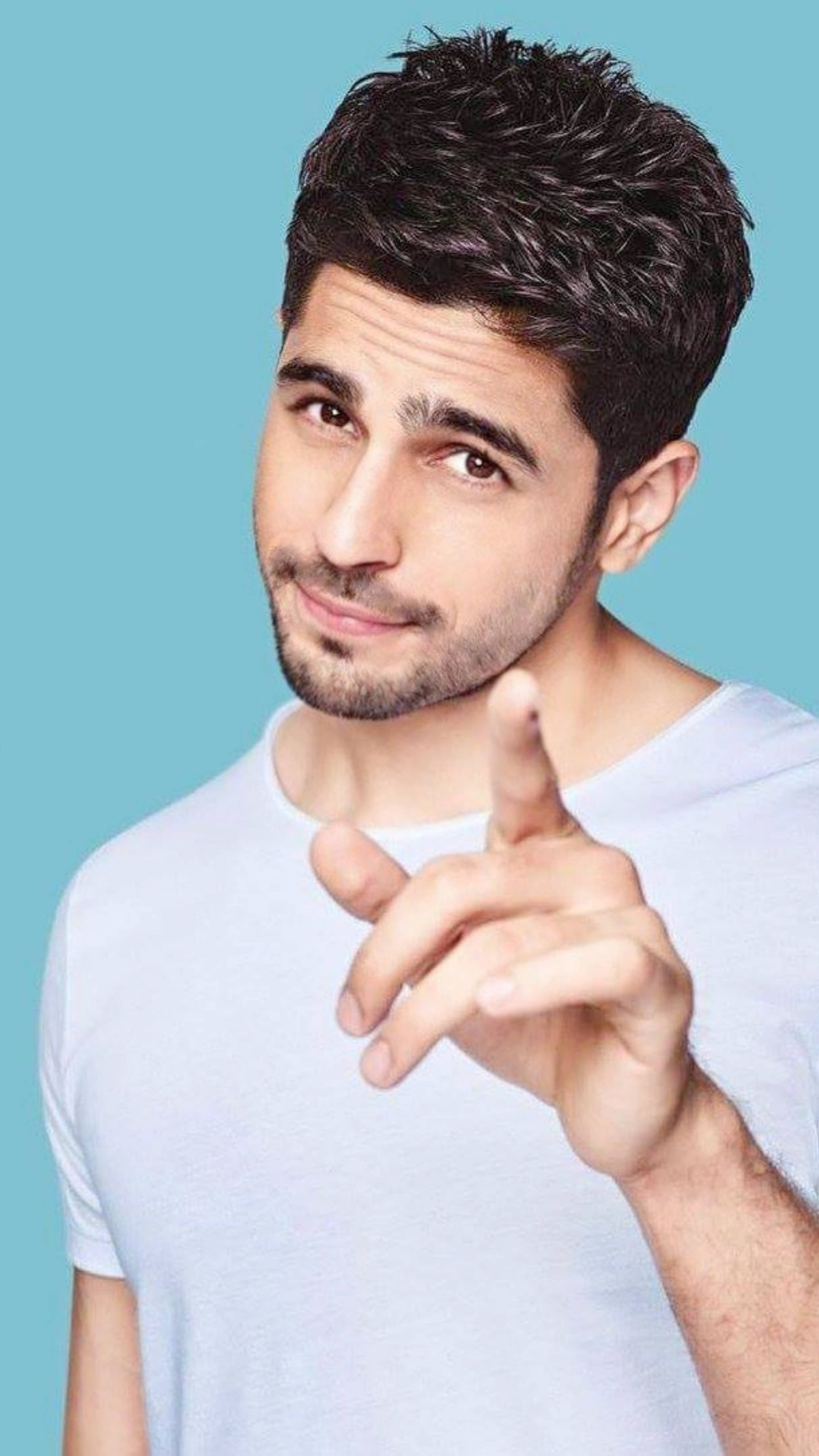 Sidharth Malhotra 桌布 壁紙 — 一位深色頭髮、留著淺鬍鬚的英俊男士，在純藍色背景前直接指向觀眾。