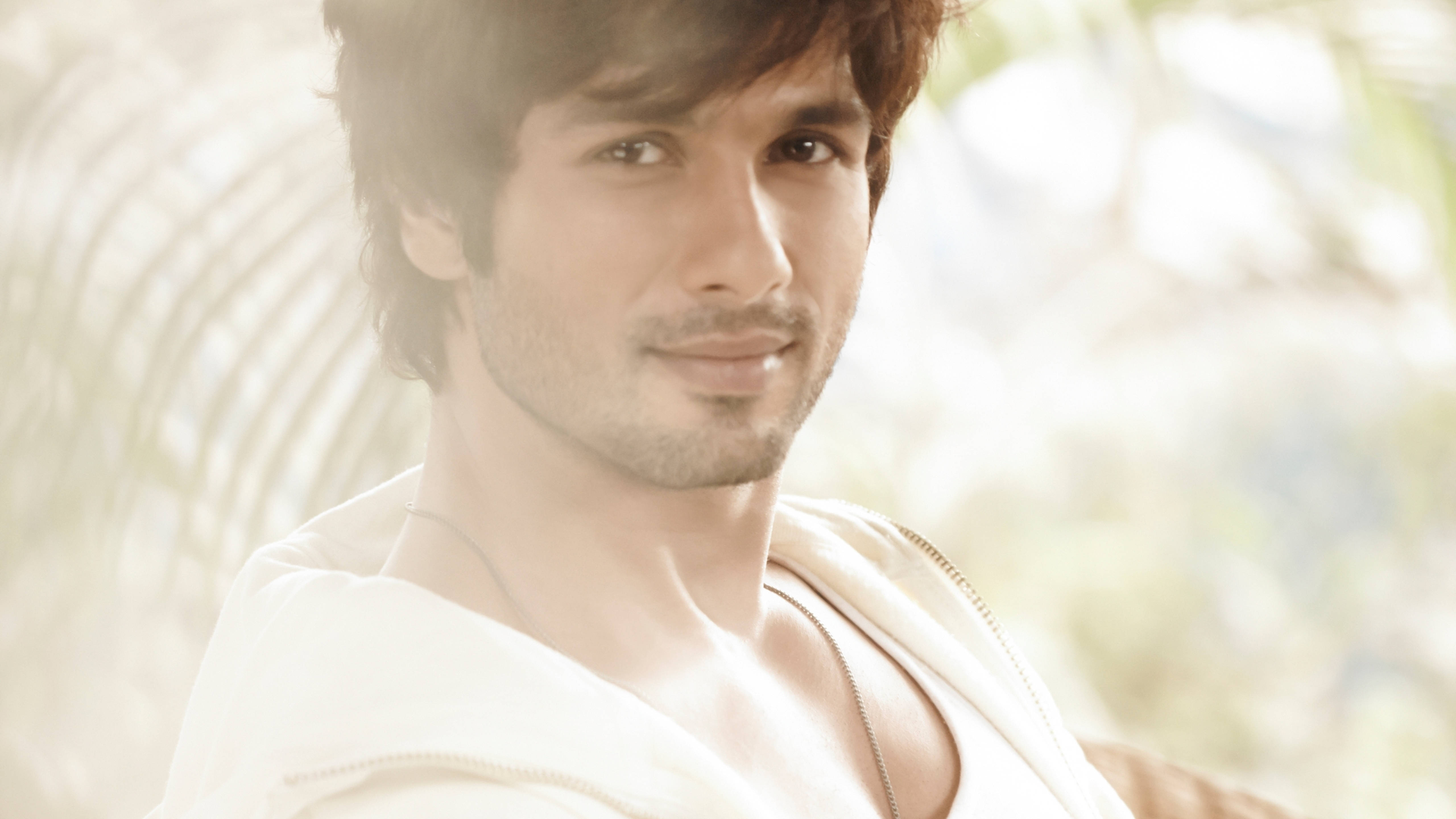 Shahid Kapoor 桌布 壁紙 — 一位深色頭髮、留著淺鬍鬚的英俊男子在溫暖的陽光下微笑，身後有模糊的棕櫚葉。