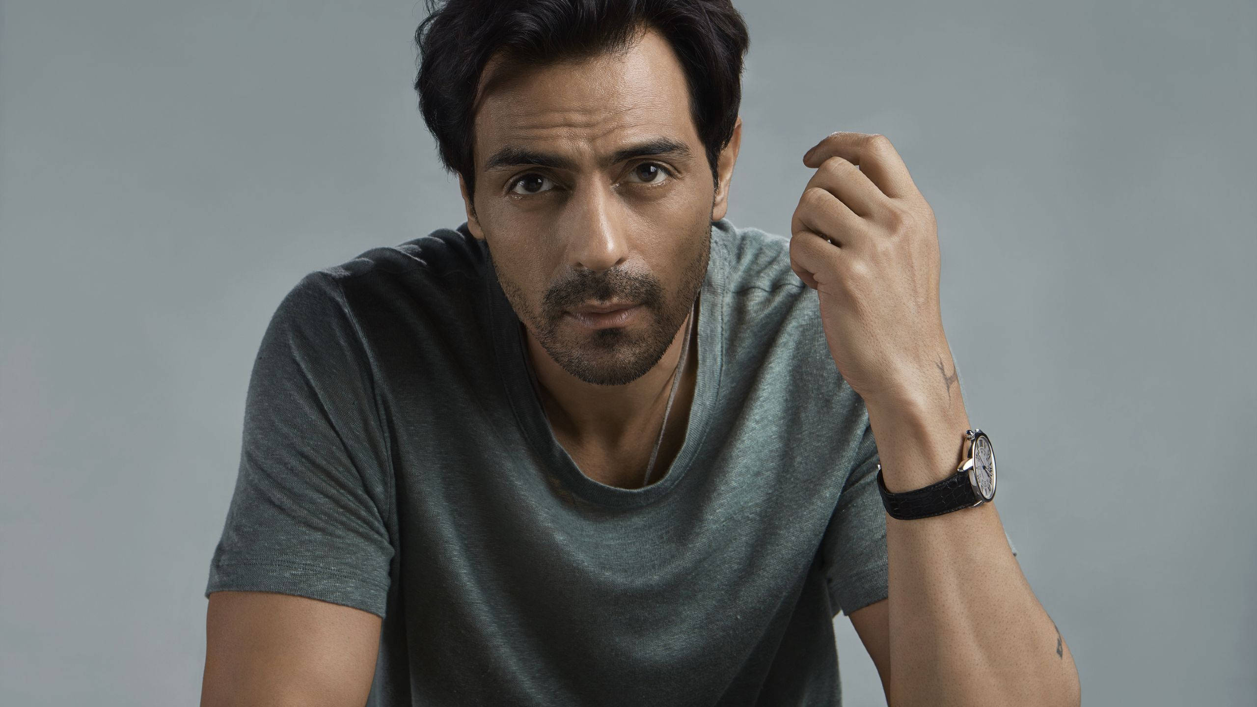 Arjun Rampal 桌布 壁紙 — 一位深色頭髮、留鬍鬚的男人，穿著灰色T恤和黑色手錶，專注地看著鏡頭。