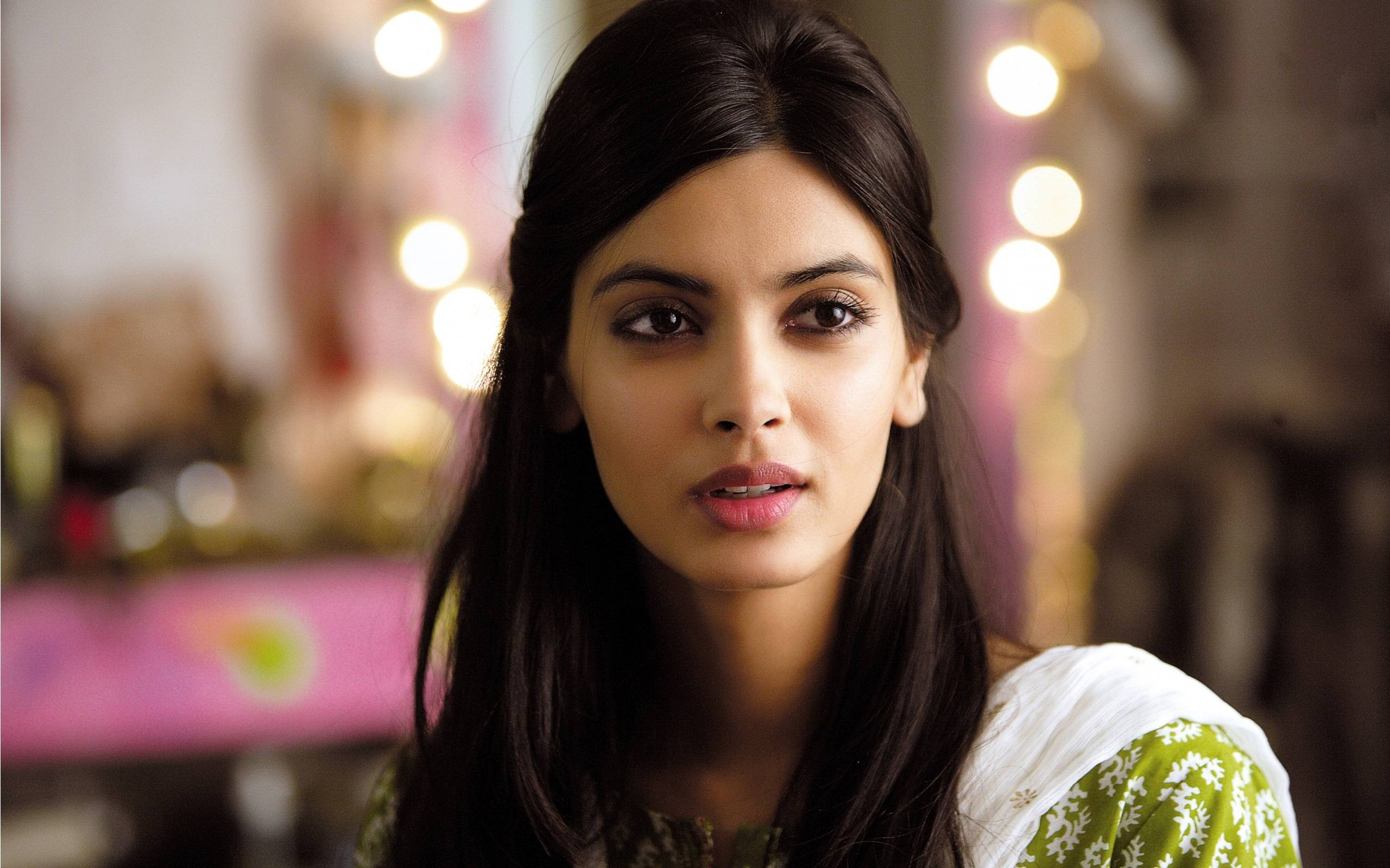 Bollywood HD 桌布 壁紙 — 一位深色頭髮、眼神強烈的女性，在柔和模糊的溫暖發光背景前向前凝視。