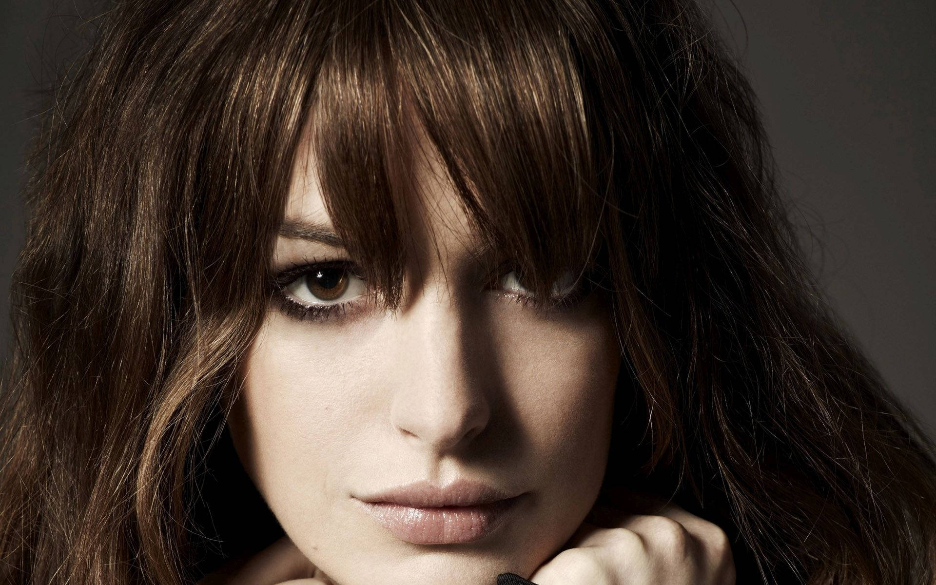 Anne Hathaway 桌布 壁紙 — 一位深色頭髮、眼神強烈的女性特寫肖像，直視鏡頭。