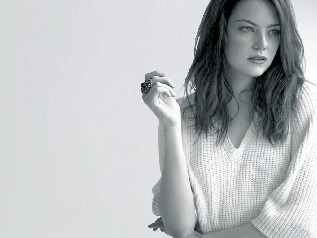Emma 桌布 壁紙 — 一位深色頭髮、穿著質感毛衣的女性，在白色背景前以單色沉思地凝視。
