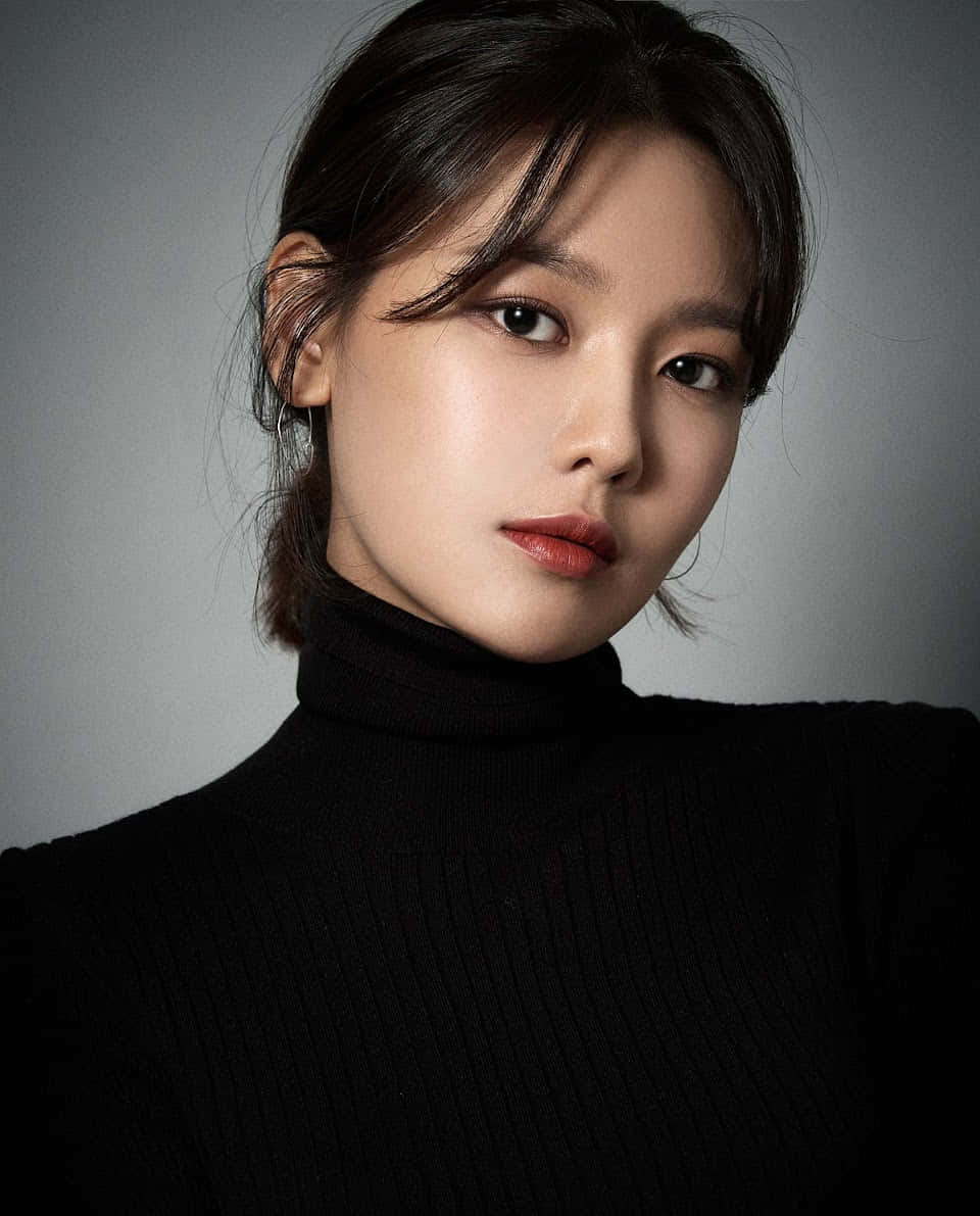 美女 桌布 壁紙 — 一位深色頭髮、紅唇的女性，穿著黑色高領毛衣，在灰色工作室背景下直視鏡頭。