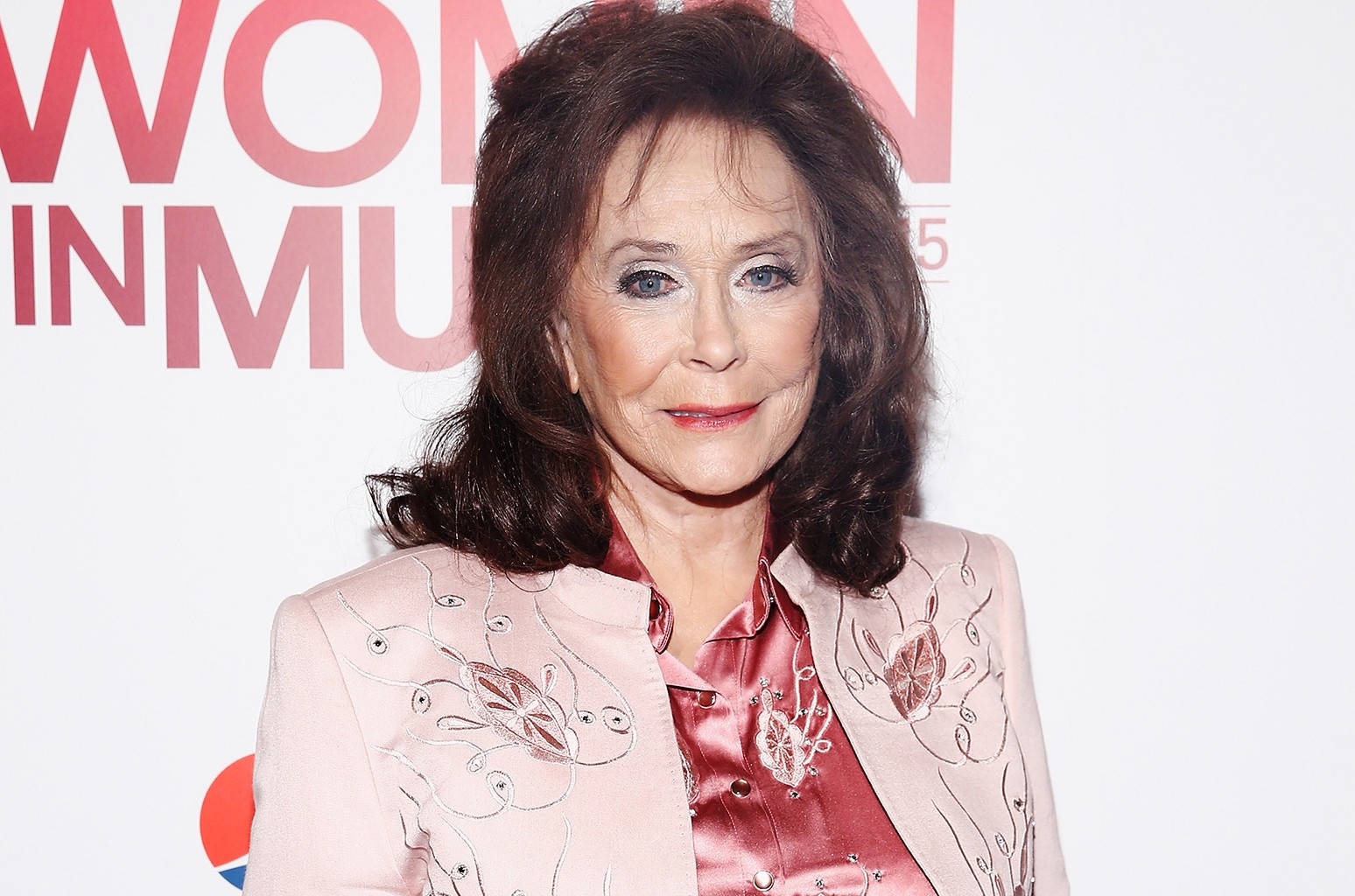 Celebrity 桌布 壁紙 — 一位深色頭髮、藍眼睛的優雅女士，在「Women in Music」活動中穿著粉紅色刺繡外套，內搭緞面襯衫。