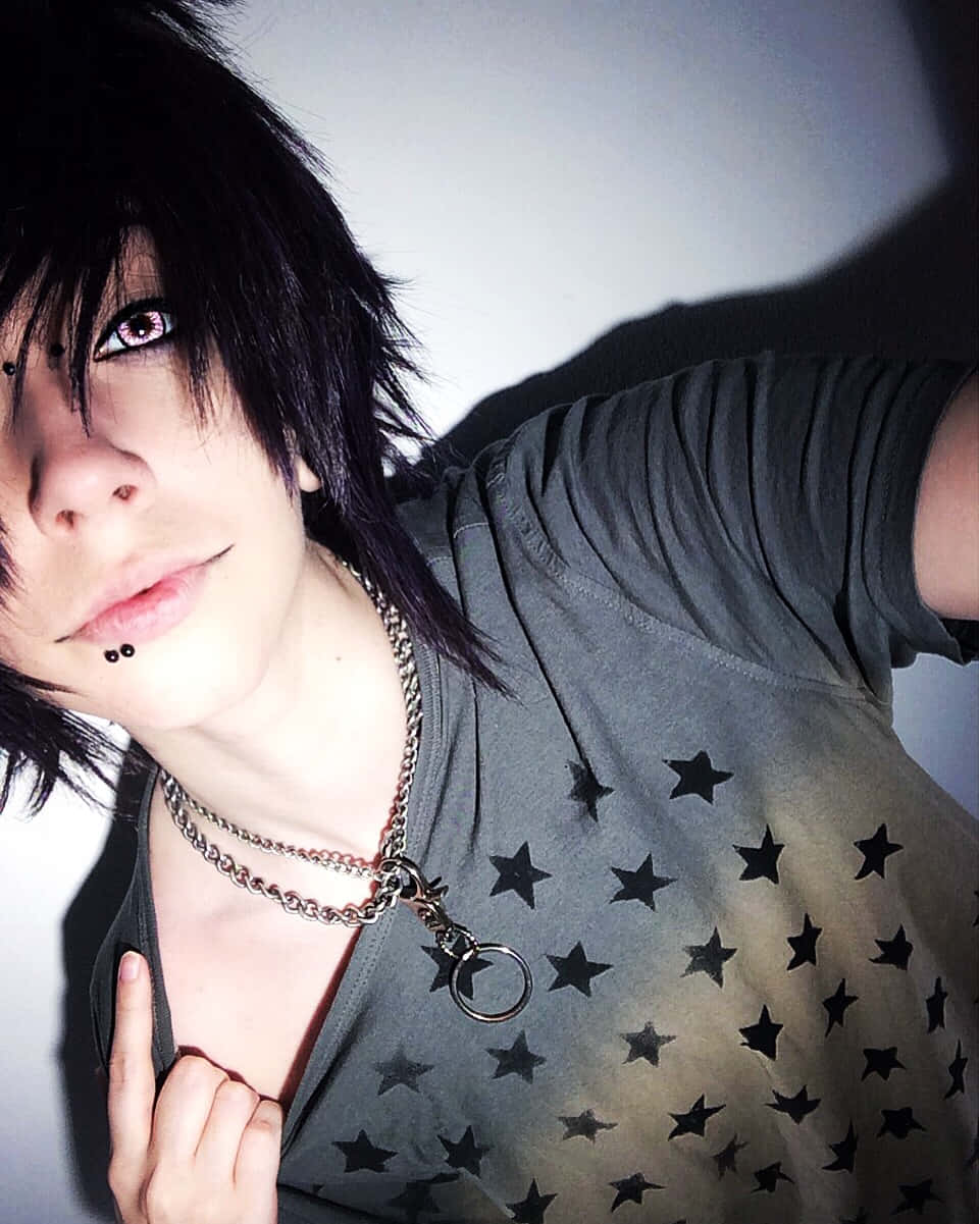 emo 美學 桌布 壁紙 — 一位深色頭髮、身穿星星圖案襯衫的人，在戲劇性的燈光下擺姿勢，露出可見的穿孔和分層鏈條。