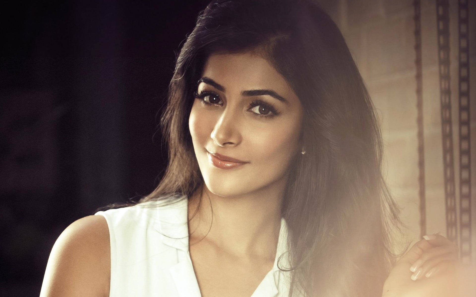 Telugu Heroines 桌布 壁紙 — 一位深色頭髮、身穿白色上衣的女性，在溫暖的金色光線下，對著模糊的背景溫柔微笑。