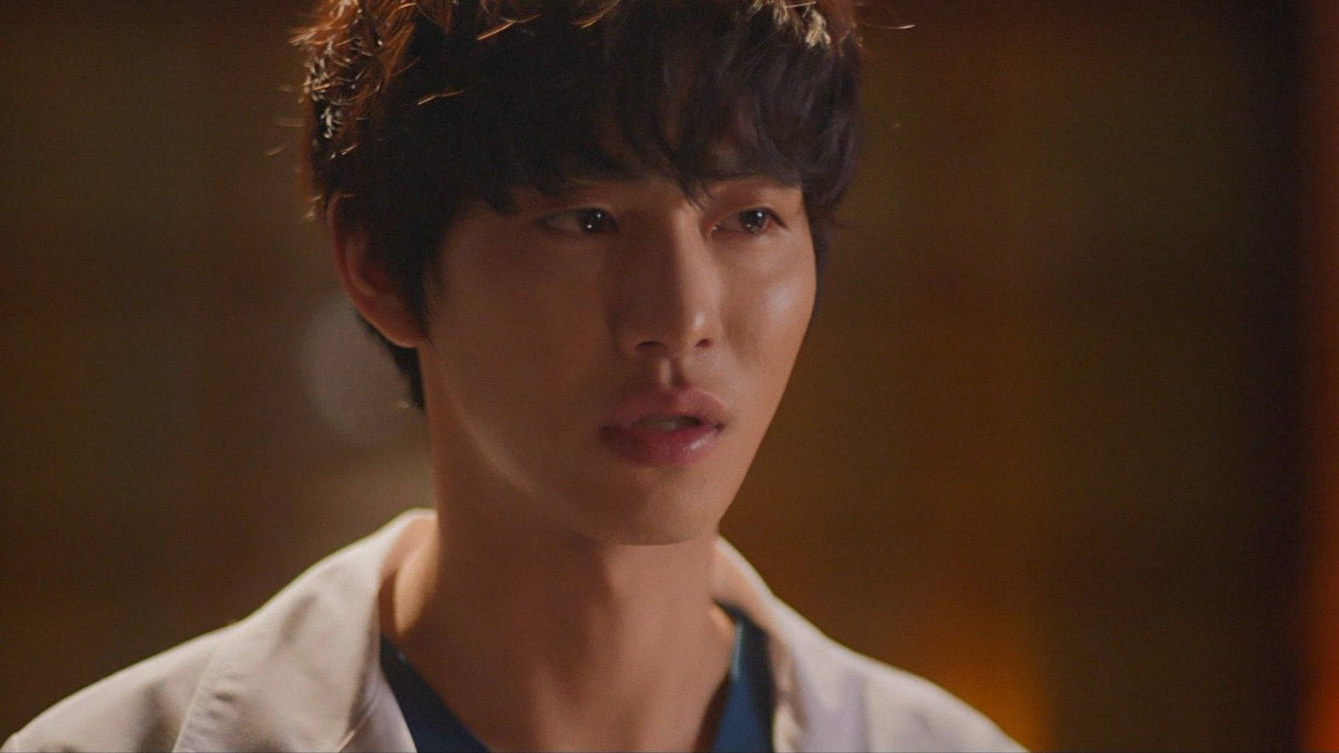 Ahn Hyo Seop 桌布 壁紙 — 一位深色頭髮、身穿白色外套的年輕男子，在溫暖模糊的背景前專注地凝視。