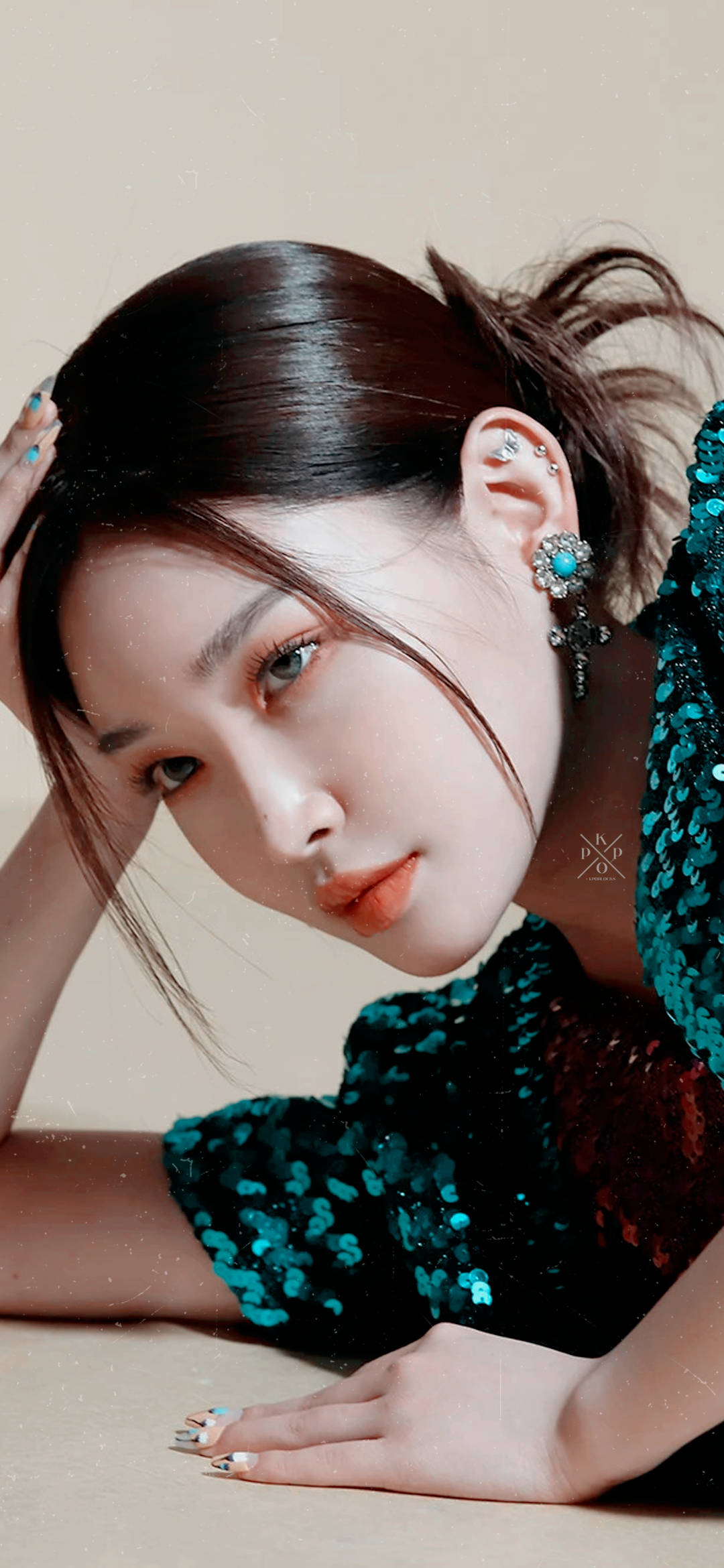 Chungha 桌布 壁紙 — 一位深色頭髮、身穿藍綠色亮片上衣的女性，在米色背景前，手放在頭上向前傾。