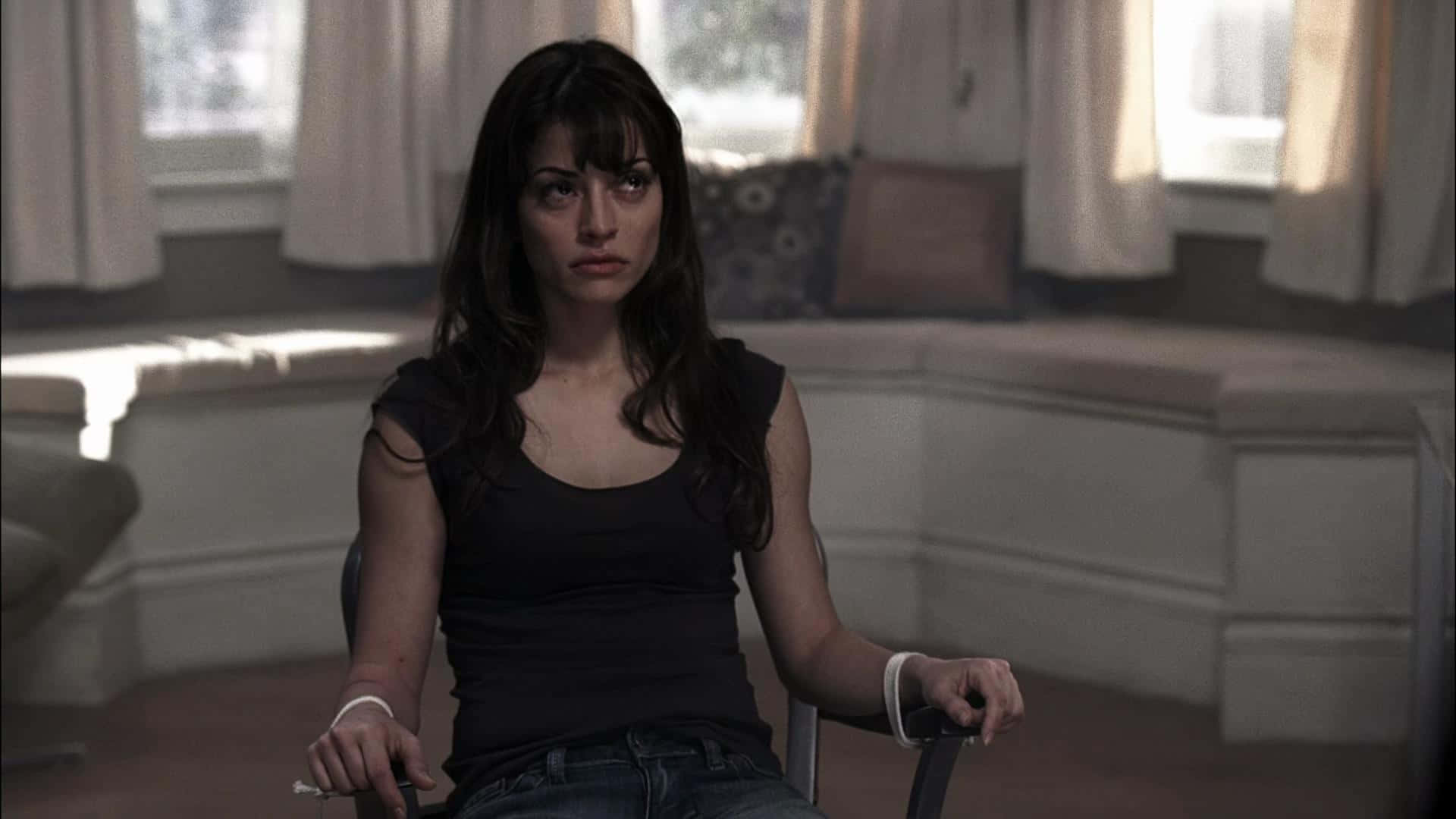 Emmanuelle Vaugier 桌布 壁紙 — 一位深色頭髮的女人坐在陽光充足的房間裡的椅子上，手裡拿著香煙，神情嚴肅。
