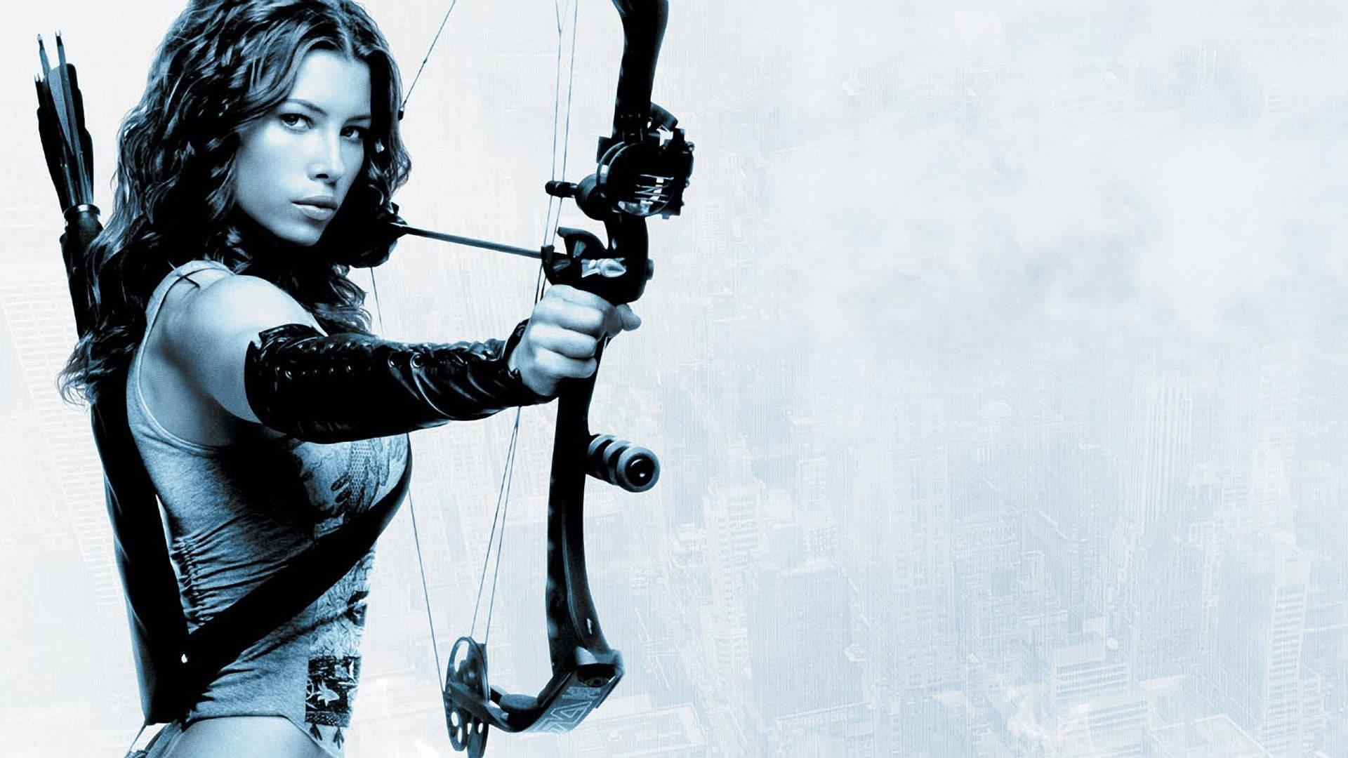 Archery 桌布 壁紙 — 一位深色頭髮的女性在朦朧的城市天際線背景下瞄準複合弓。