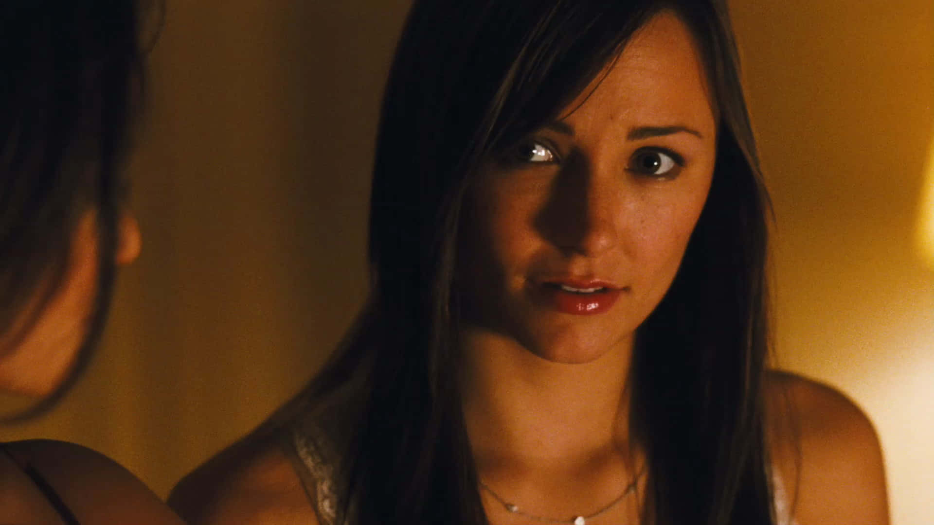 Briana Evigan 桌布 壁紙 — 一位深色頭髮的女性在溫暖燈光的室內環境中專注地看著另一個人。
