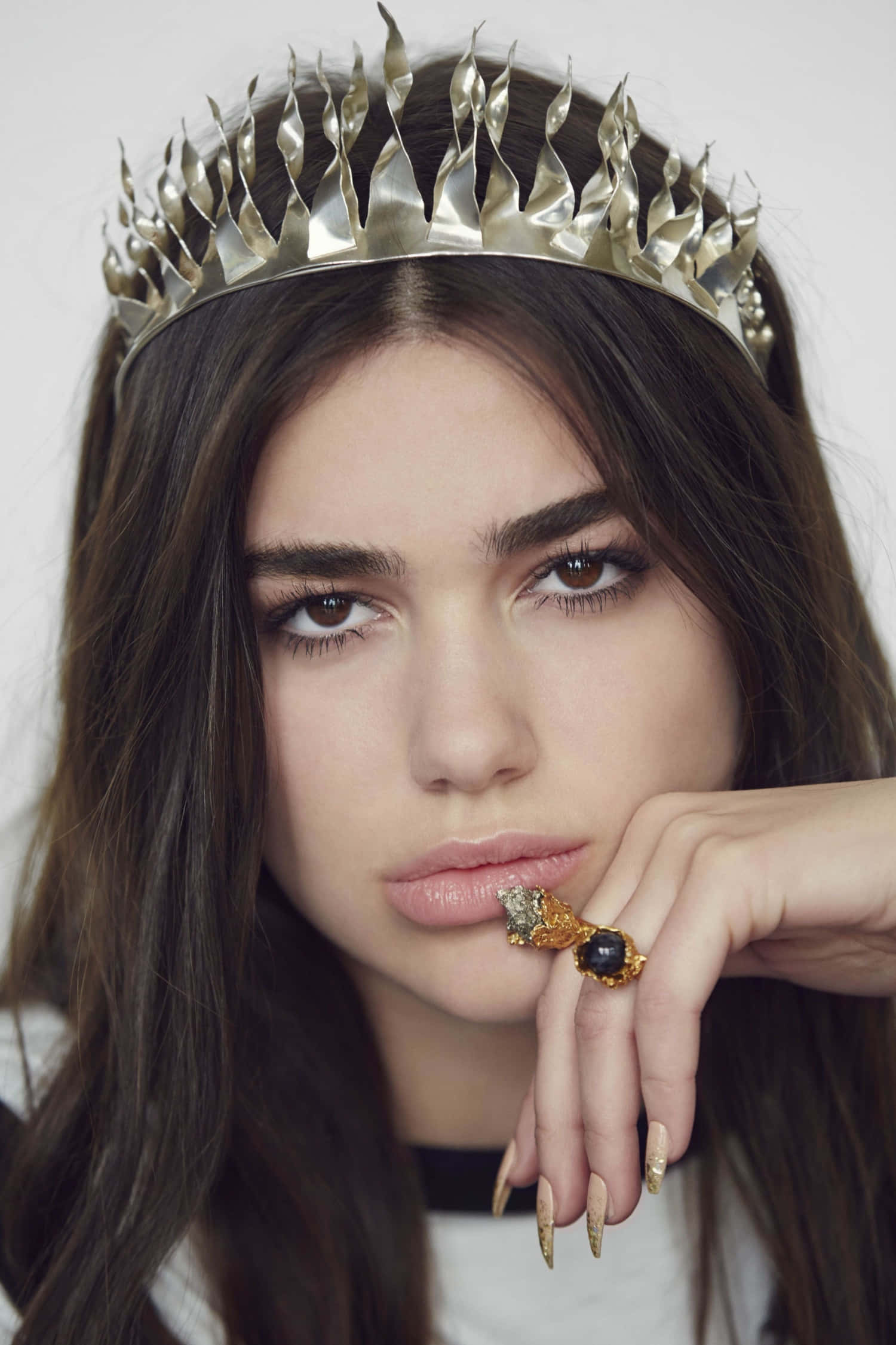 Dua Lipa 桌布 壁紙 — 一位深色頭髮的女性戴著帶有尖刺的金屬皇冠和一個華麗的大戒指，專注地凝視著鏡頭。