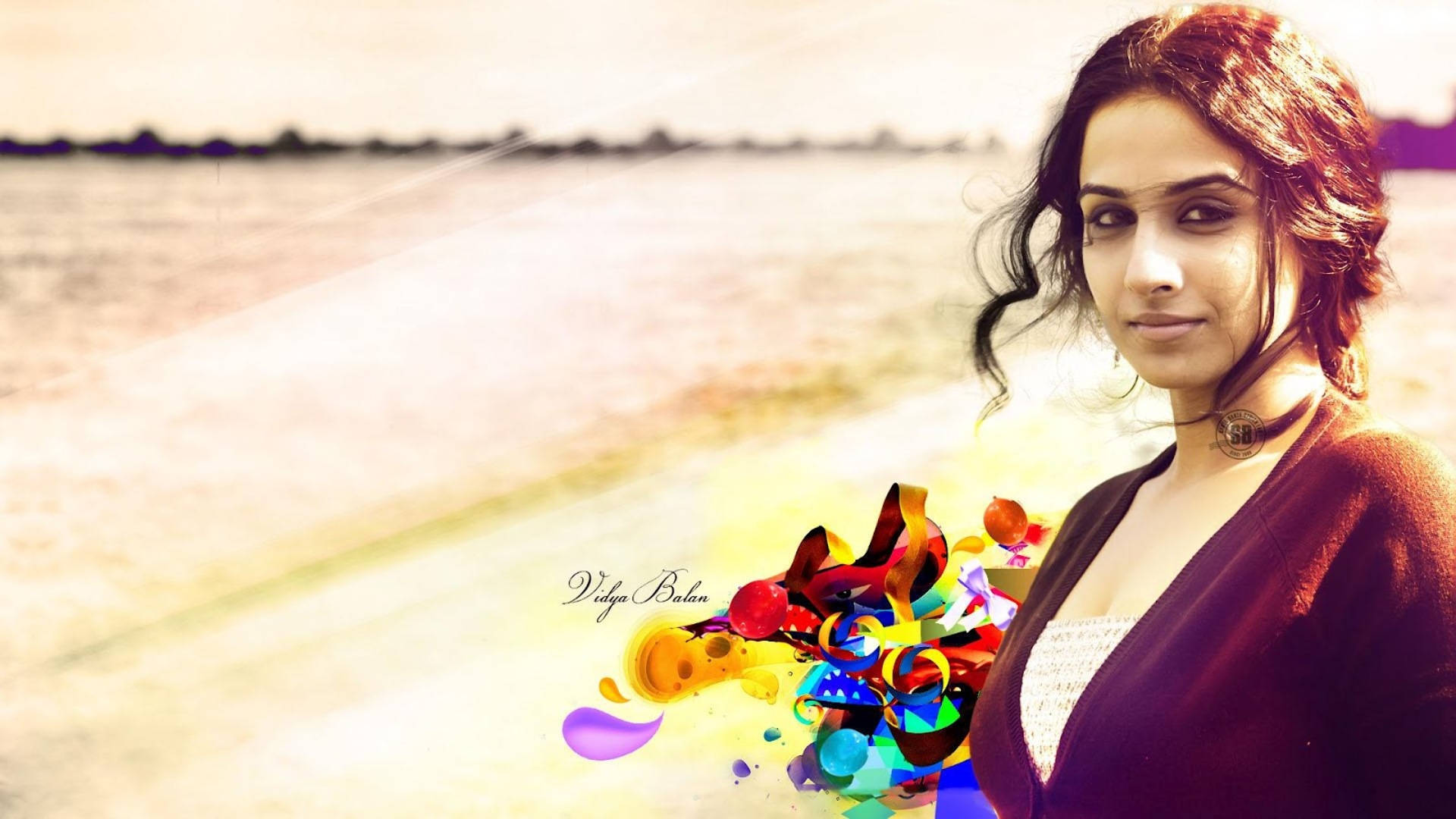 Vidya Balan 桌布 壁紙 — 一位深色頭髮的女性站在水邊，在朦朧的金色背景下手持色彩繽紛的抽象形狀爆發。