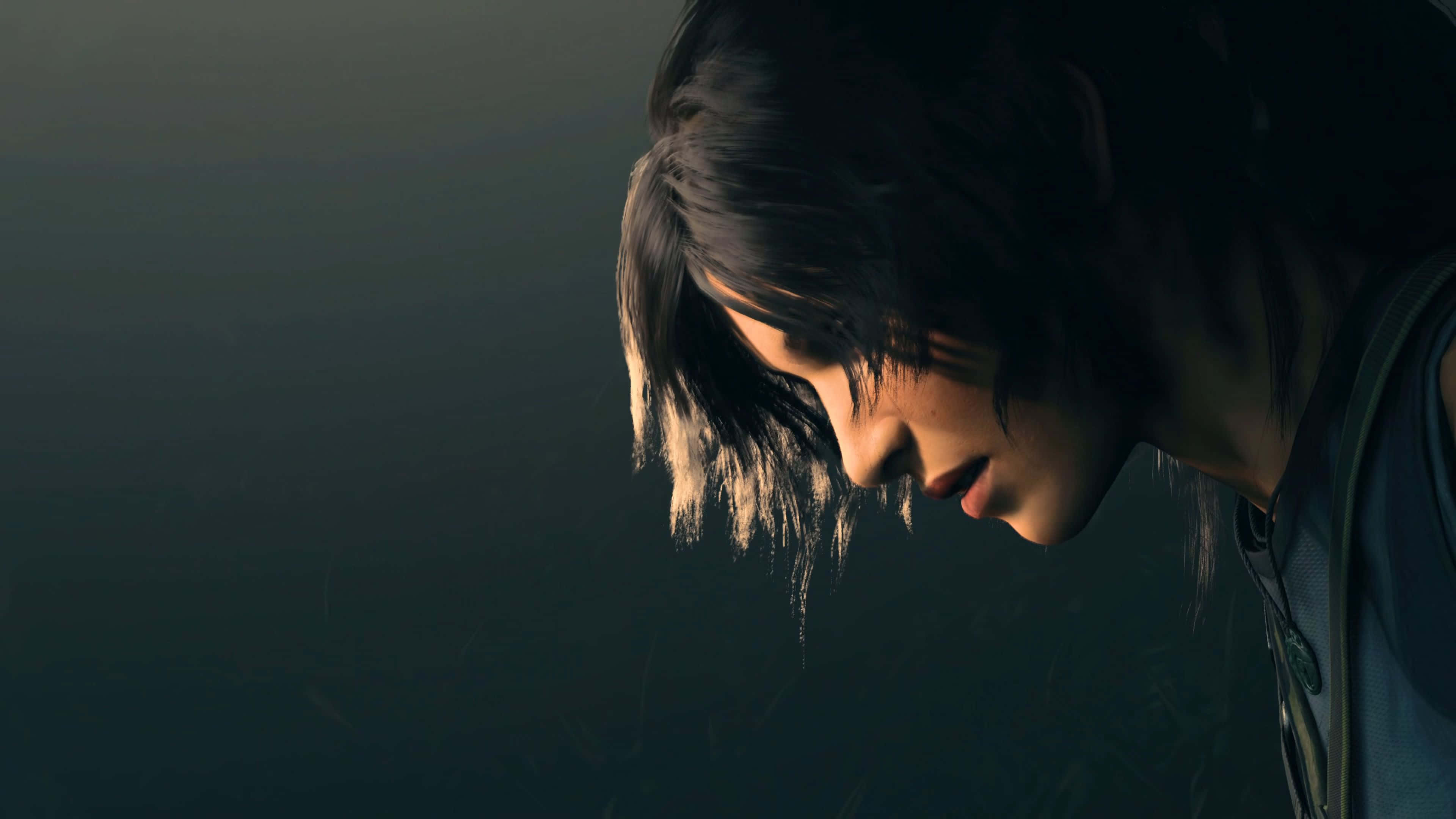 Lara Croft 桌布 壁紙 — 一位深色頭髮的年輕人低頭沉思，背景陰暗而充滿氛圍。