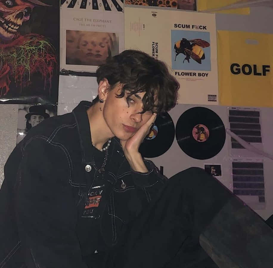 Boy 桌布 壁紙 — 一位深色頭髮的年輕人將頭靠在手上，倚著一面貼滿音樂海報和黑膠唱片的牆壁。