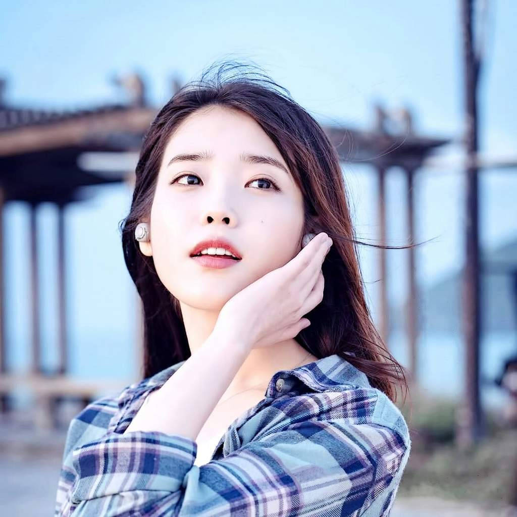 Kpop Aesthetic 桌布 壁紙 — 一位深色頭髮的年輕女性在柔和光線的戶外環境中輕輕觸摸臉頰，向上凝視。