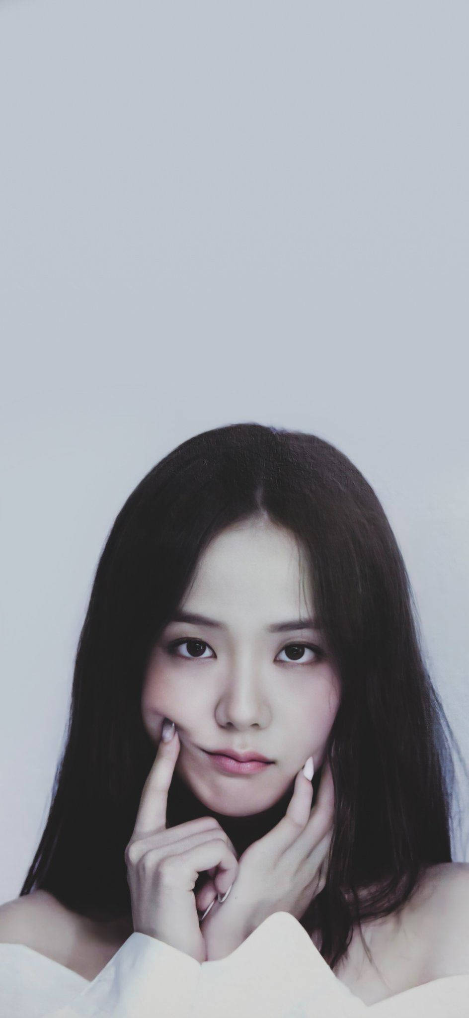 Jisoo Cute 桌布 壁紙 — 一位深色頭髮的年輕女性在柔和的灰色背景上輕輕觸碰臉頰，呈現極簡肖像風格。