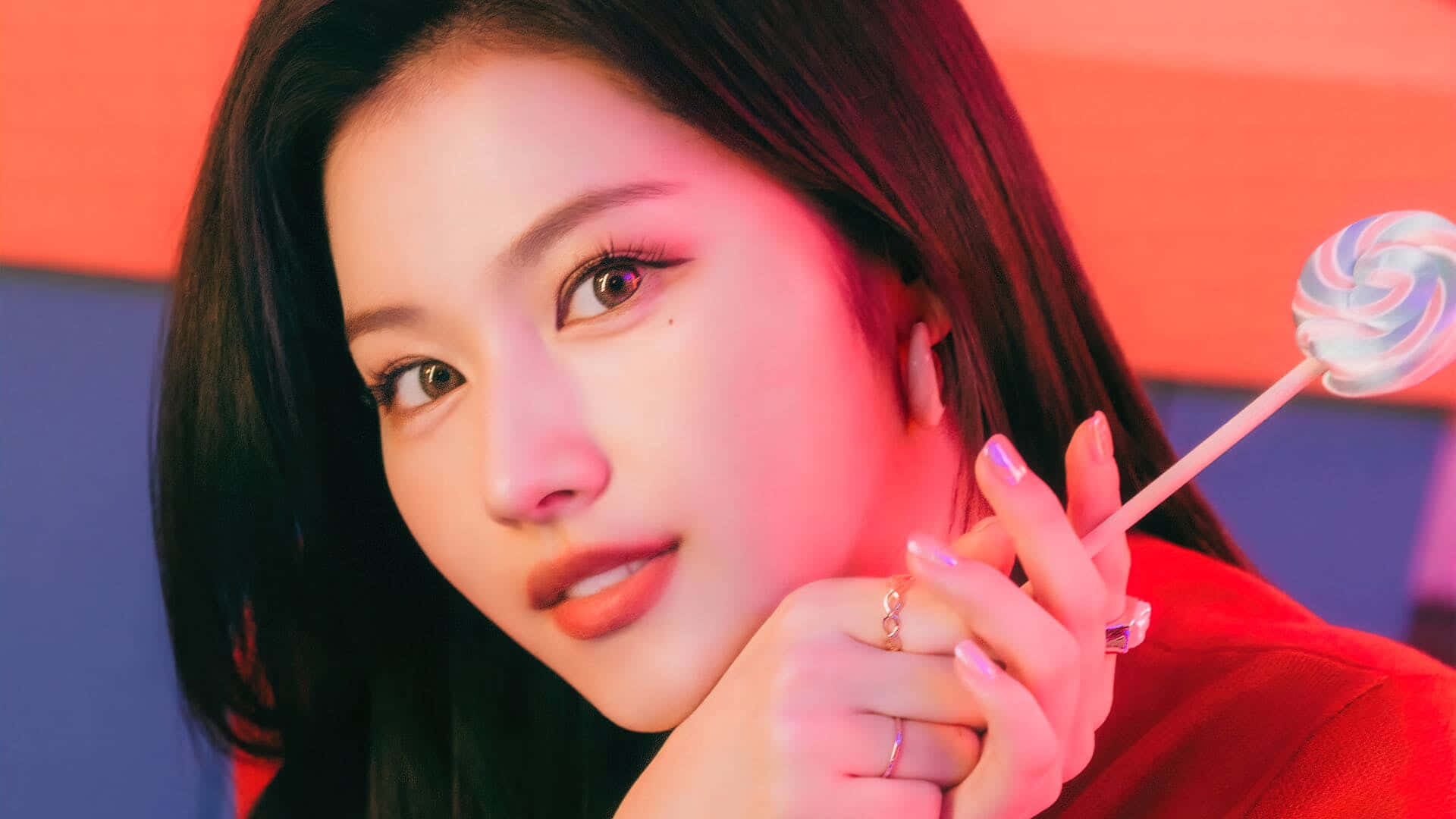 twice 桌布 壁紙 — 一位深色頭髮的年輕女性在霓虹燈光下，手持色彩繽紛的棒棒糖，背景是鮮豔的紅色和藍色。