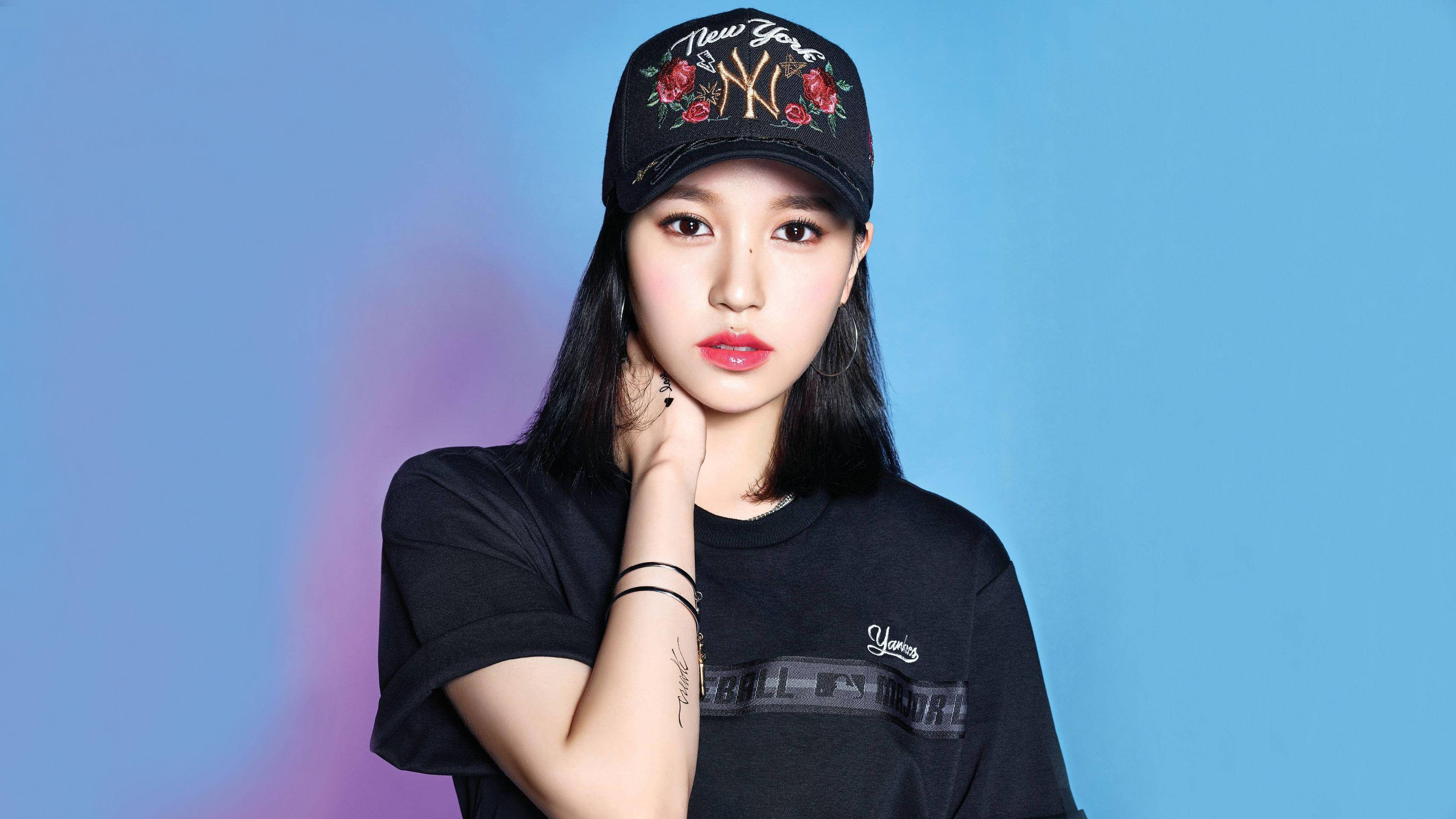 Twice Mina 桌布 壁紙 — 一位深色頭髮的年輕女性戴著帶有紅玫瑰的黑色帽子，穿著黑色T恤，背景是藍色和紫色的漸變色。