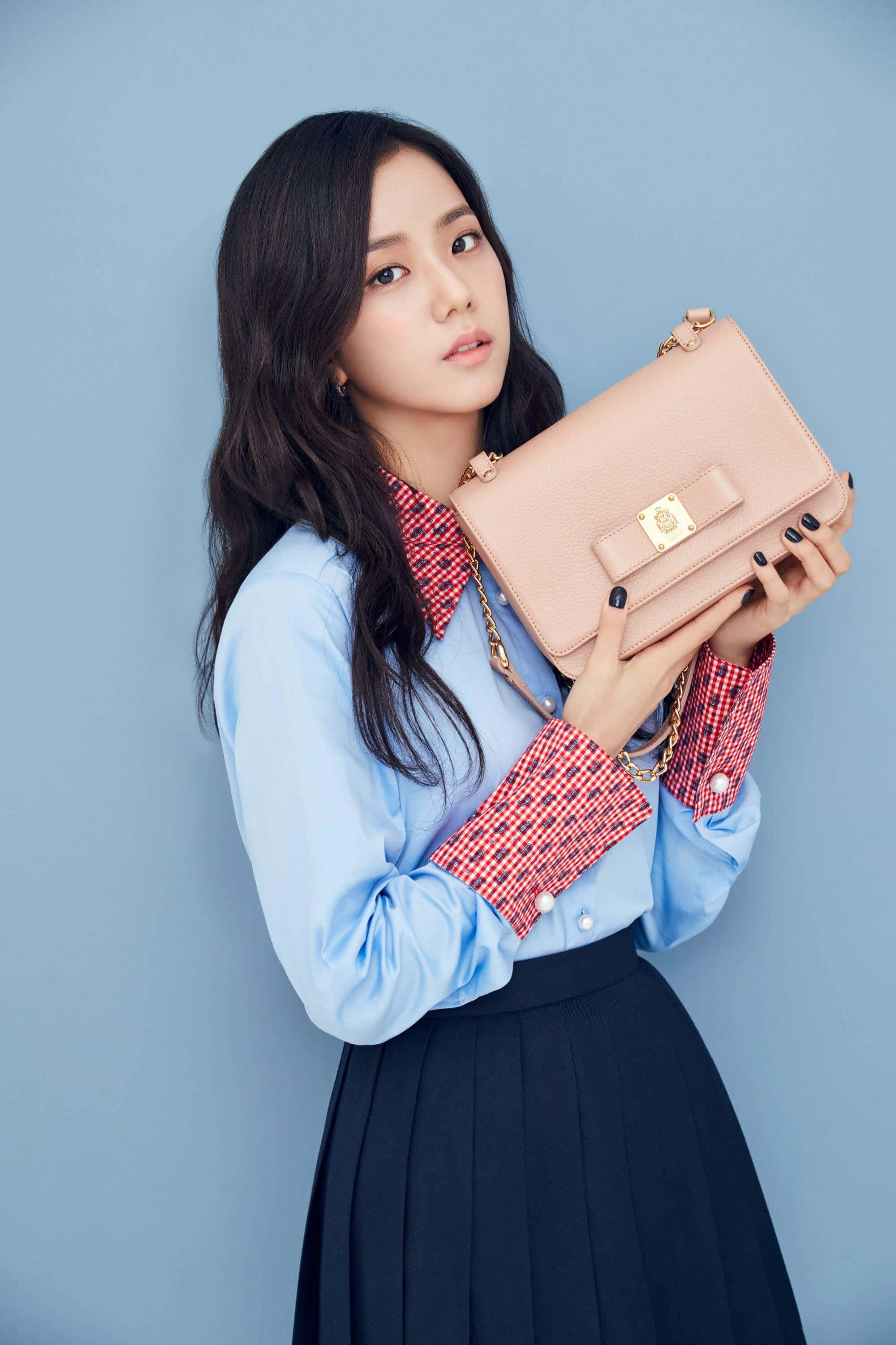 BLACKPINK 桌布 壁紙 — 一位深色頭髮的年輕女性拿著一個腮紅粉紅色手提包，背景是純藍色攝影棚。