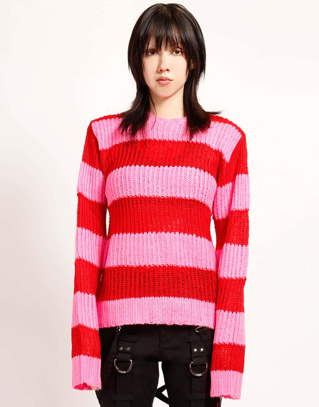 Red Sweater 桌布 壁紙 — 一位深色頭髮的年輕女性穿著大膽的紅粉條紋針織毛衣，搭配黑色戰術褲，背景為純白色。