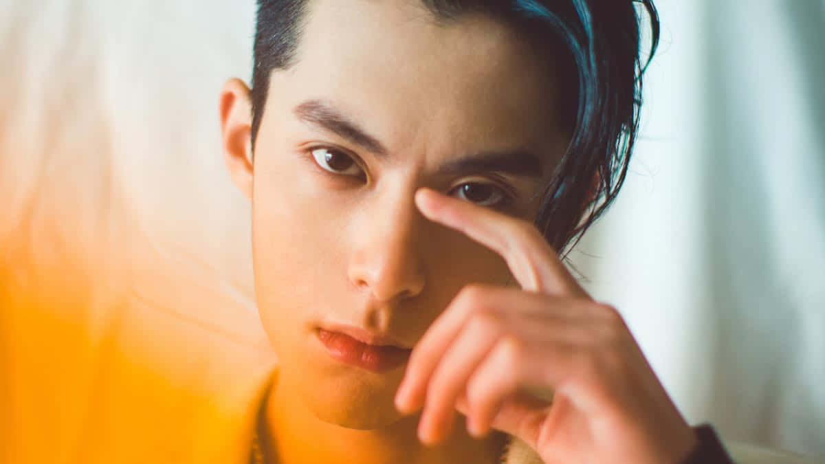 Dylan Wang 桌布 壁紙 — 一位深色頭髮的年輕男子在柔和模糊的背景中，用手指觸碰眼睛，目光專注。