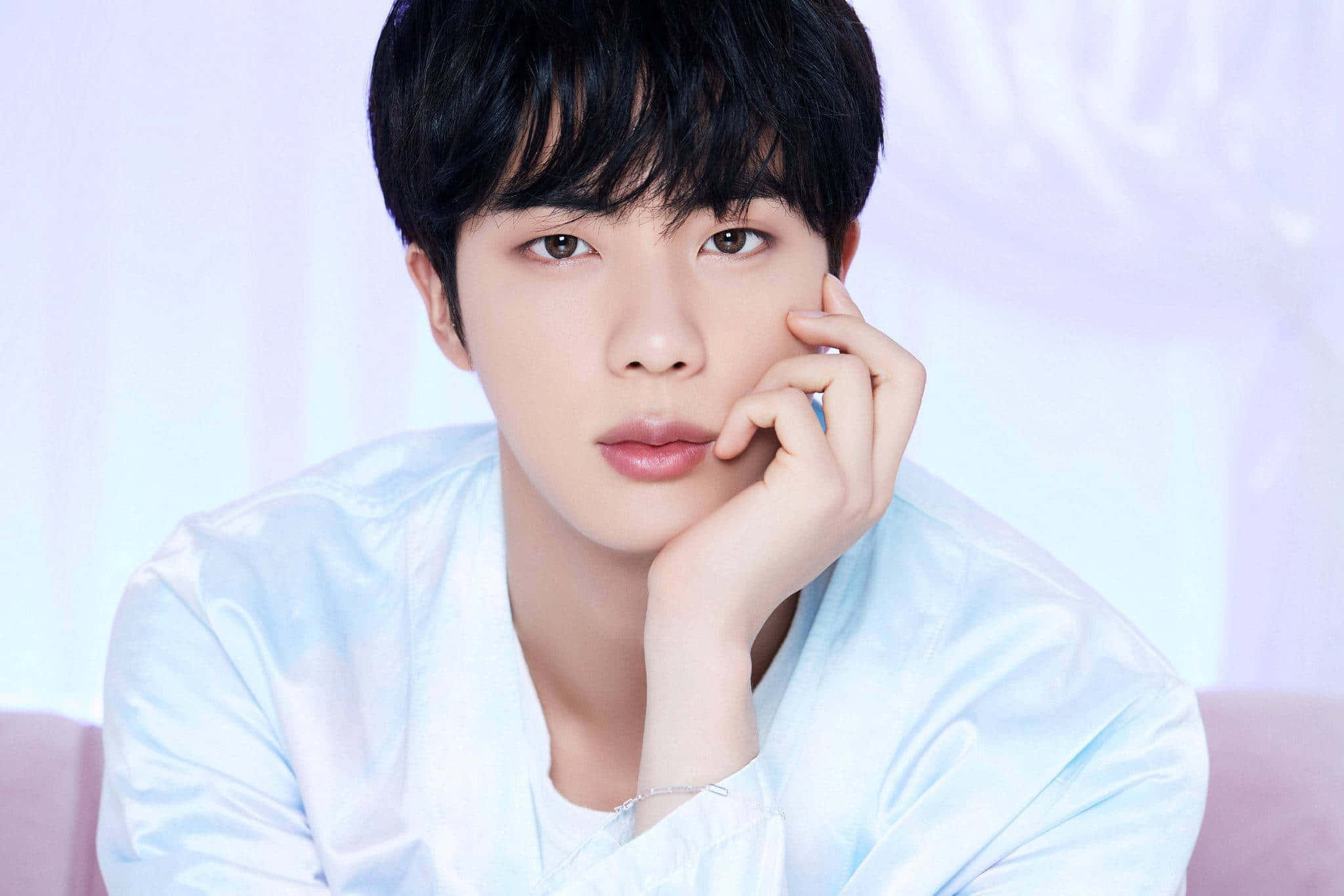 Jin 桌布 壁紙 — 一位深色頭髮的年輕男子將下巴擱在手上，背景是柔和的粉彩色。