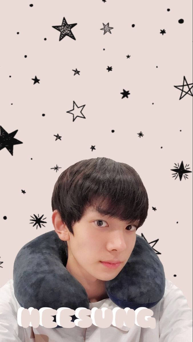 Kpop Aesthetic 桌布 壁紙 — 一位深色頭髮的年輕男子戴著灰色頸枕，背景是米色並點綴著黑色星星。