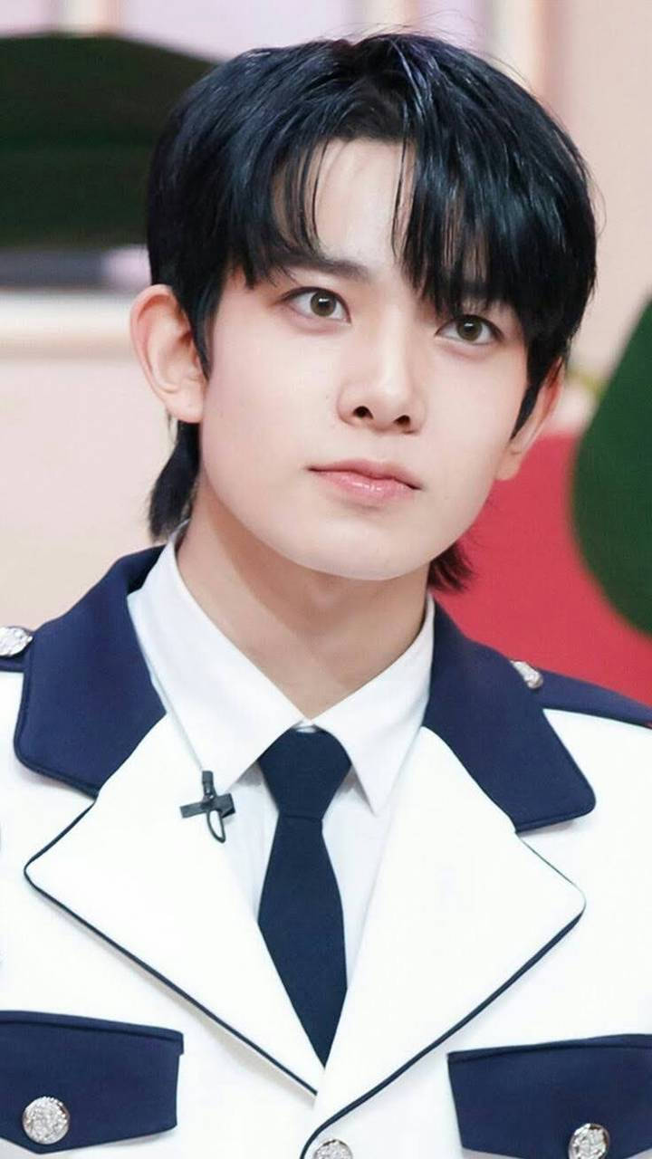 Kpop Aesthetic 桌布 壁紙 — 一位深色頭髮的年輕男子穿著整潔的白色和海軍藍色制服，配有銀色鈕扣和黑色領帶。