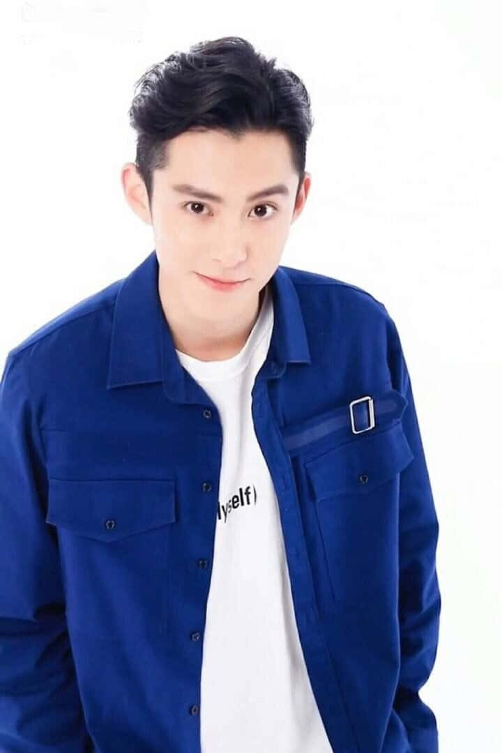 Dylan Wang 桌布 壁紙 — 一位深色頭髮的年輕男子穿著藍色鈕扣襯衫，內搭印有文字的白色T恤，背景為純白色。