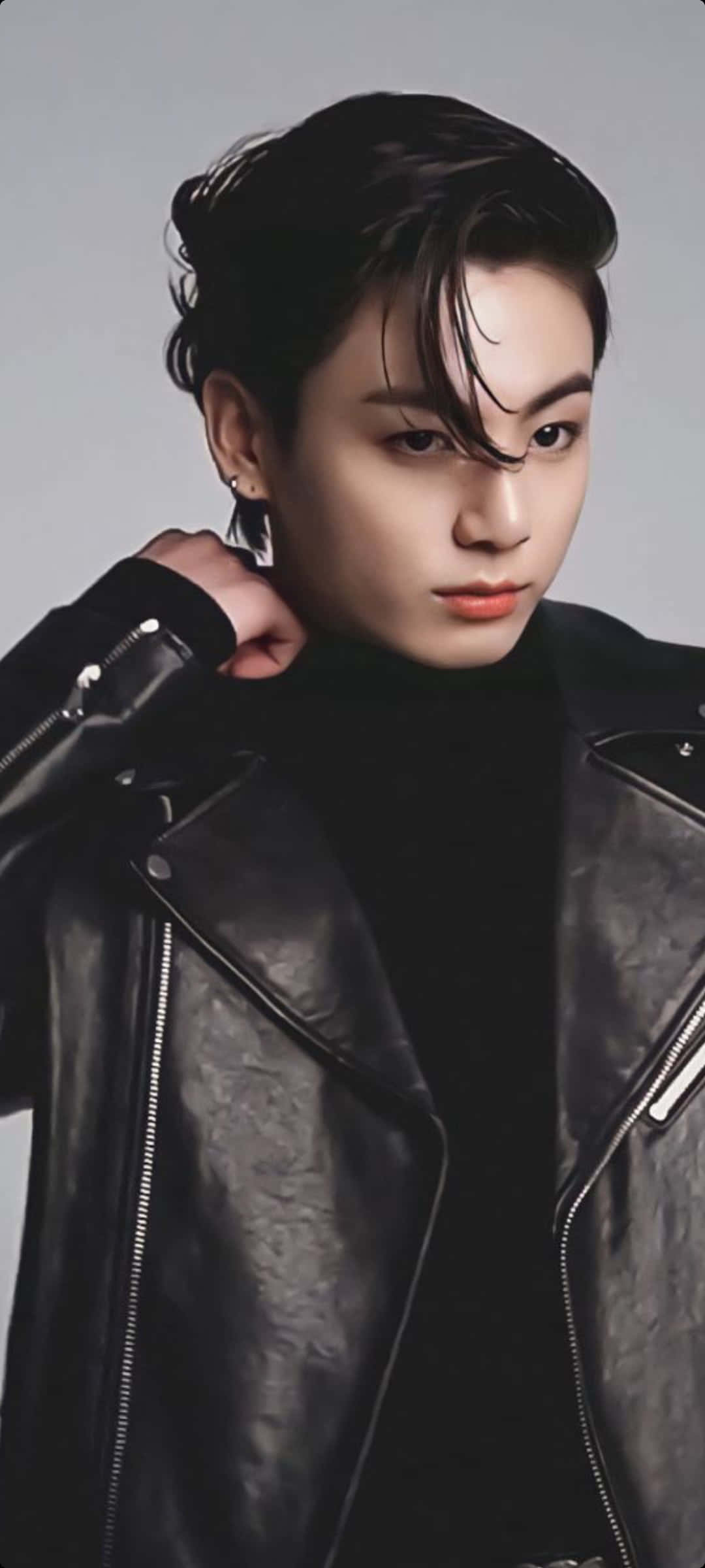 Jungkook 桌布 壁紙 — 一位深色頭髮的年輕男子穿著黑色皮夾克，背景為純灰色。