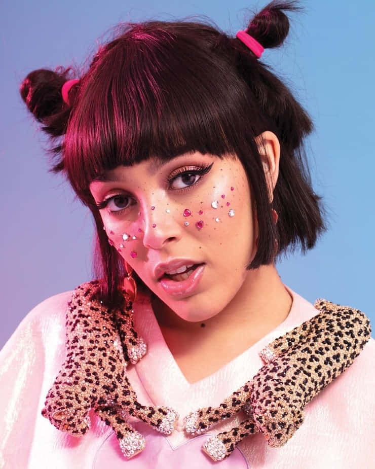 Doja Cat 桌布 壁紙 — 一位深色鮑伯頭、綁著粉紅色蝴蝶結包頭的年輕女性，在漸層藍色背景前穿著閃亮的豹紋領口。