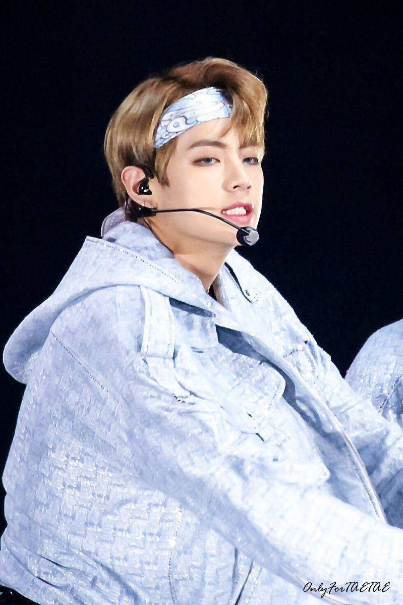 Taehyung Cute 桌布 壁紙 — 一位淺棕色頭髮、戴著圖案頭帶的年輕男子，身穿質感淺藍色外套，在明亮燈光下於舞台上表演。
