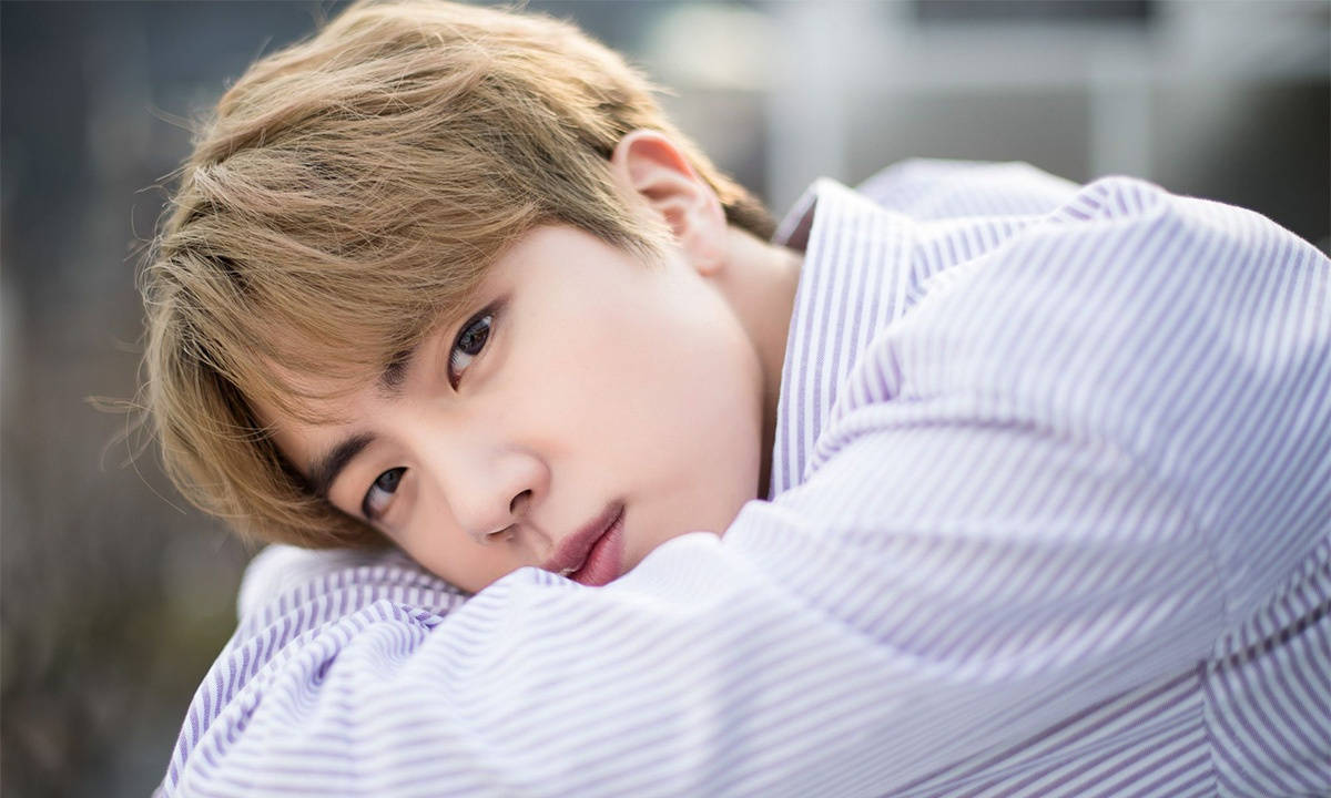 kim seok jin 桌布 壁紙 — 一位淺棕色頭髮的年輕男子將頭靠在條紋襯衫上，直視鏡頭，表情柔和。