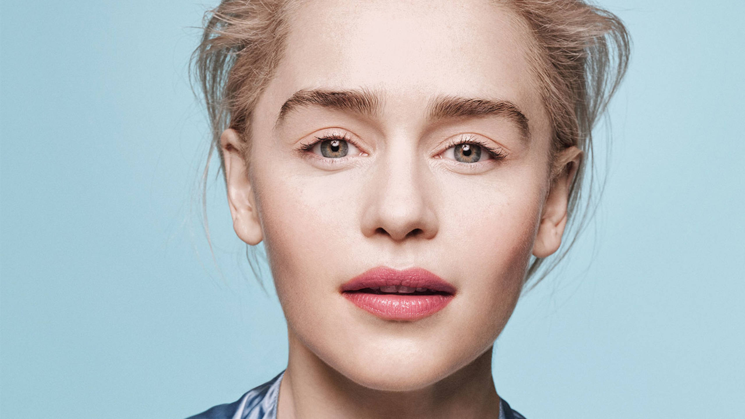 Emilia 桌布 壁紙 — 一位淺色頭髮、淡妝的女性特寫肖像，背景為純藍色。