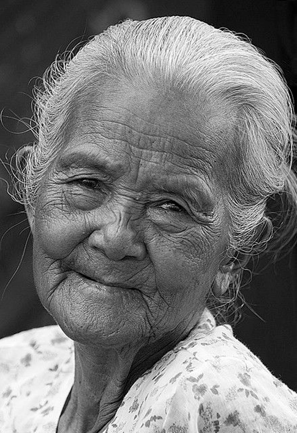 Woman 桌布 壁紙 — 一位滿臉深皺紋的年長女性對著鏡頭溫暖微笑的特寫黑白肖像。