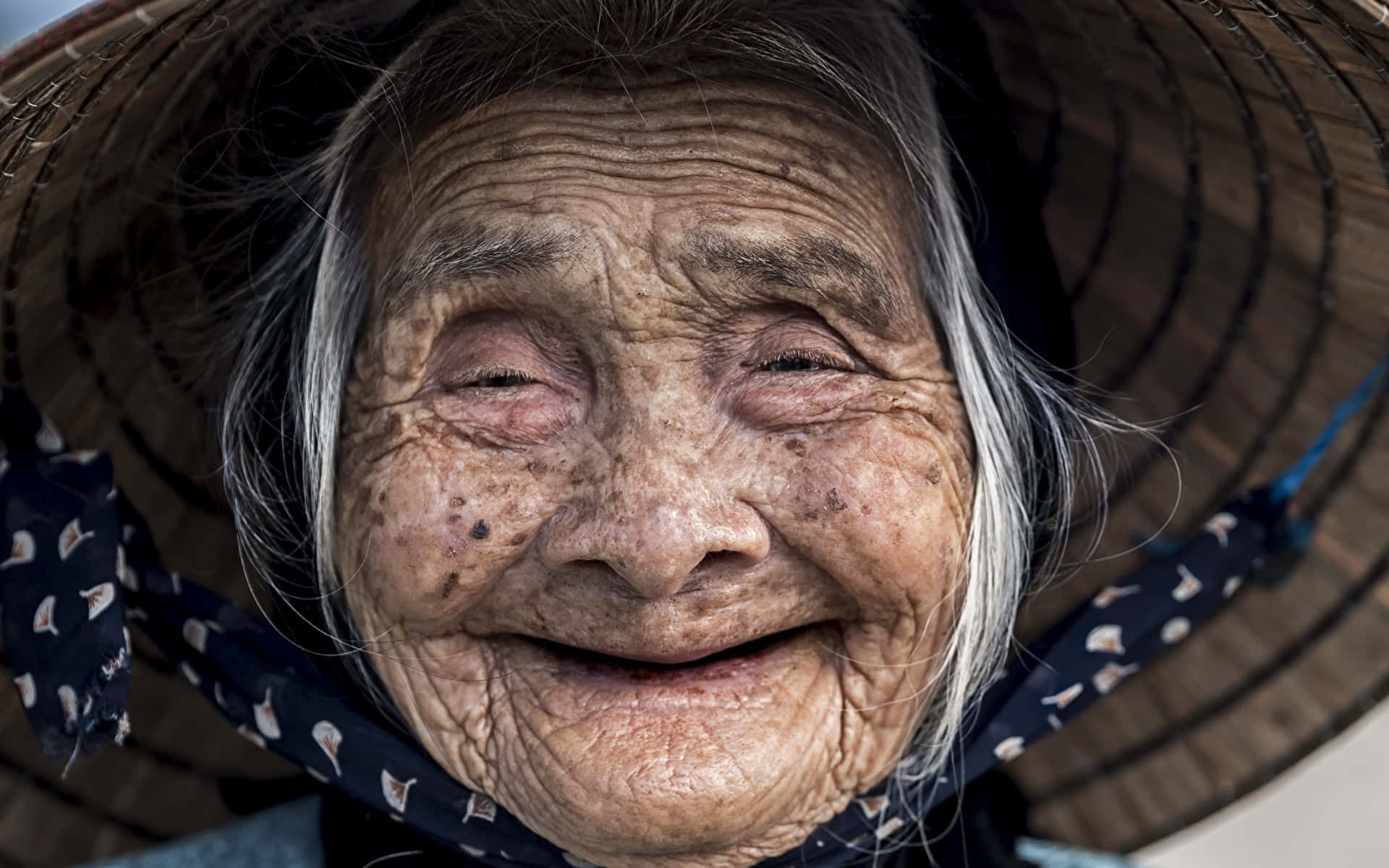 Asian Woman 桌布 壁紙 — 一位滿臉皺紋、笑容滿面的老婦人戴著傳統的圓錐形帽子。