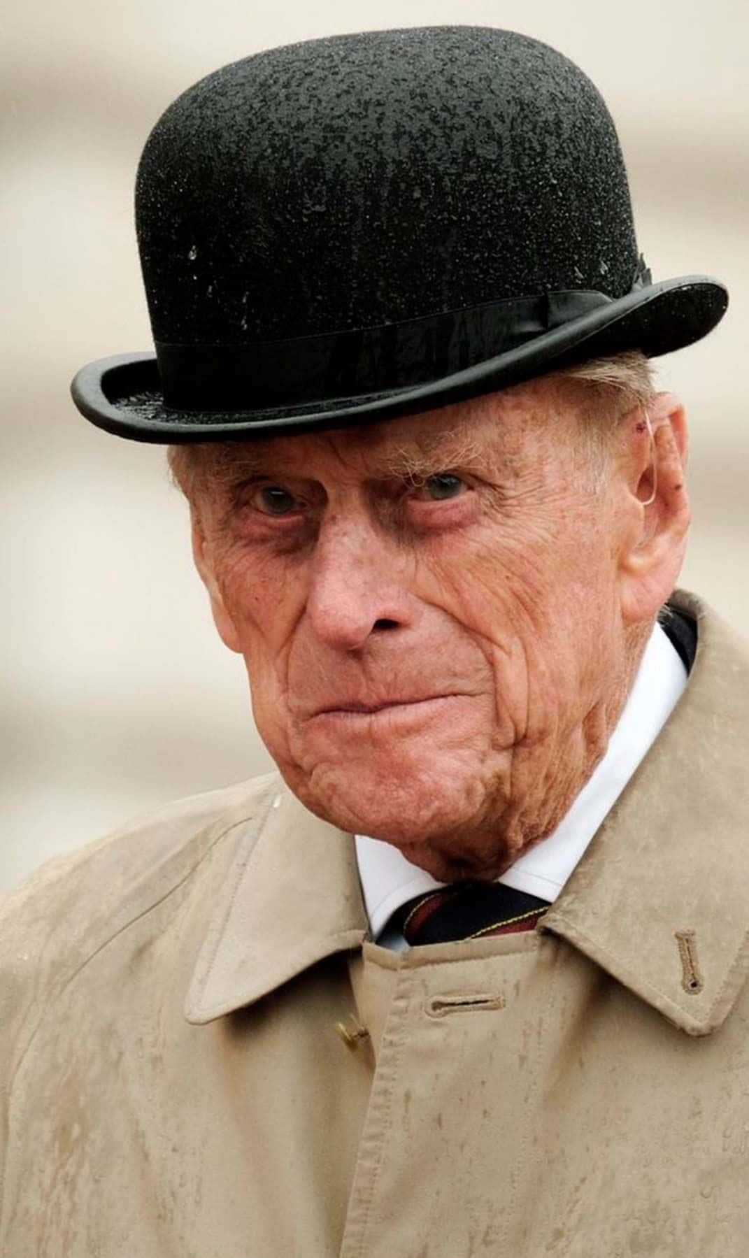 Prince 桌布 壁紙 — 一位滿臉皺紋的長者，戴著黑色圓頂硬禮帽，身穿米色風衣，背景模糊。