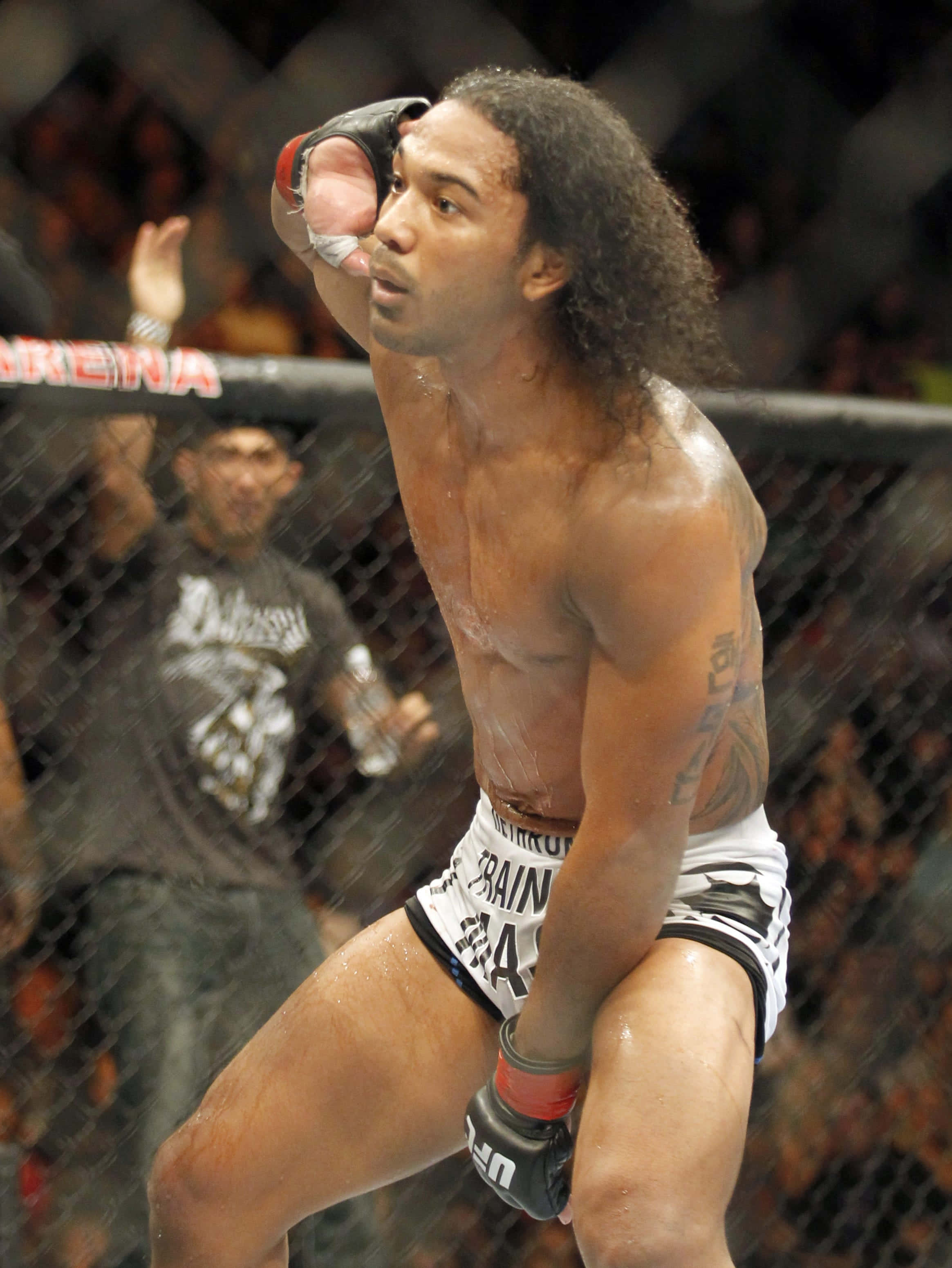 MMA 桌布 壁紙 — 一位滿身大汗、留著長捲髮的MMA拳手在八角籠內慶祝一場艱苦的比賽勝利。