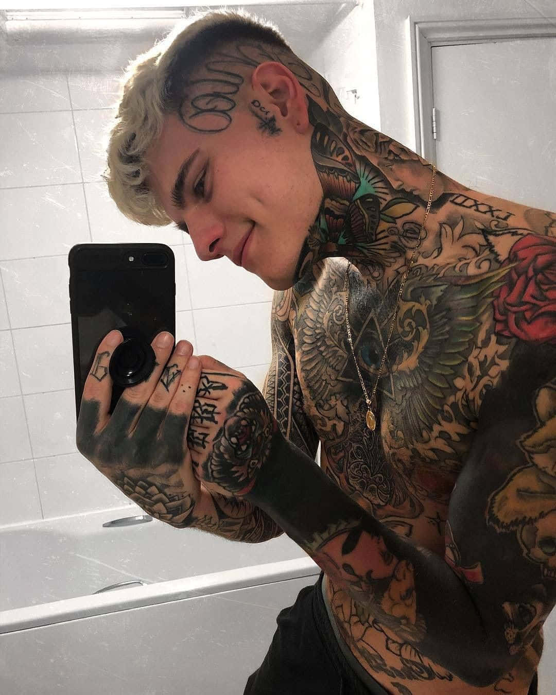 Tattoo Boy 桌布 壁紙 — 一位漂染金髮的刺青男子在磁磚浴室中對著鏡子自拍，露出覆蓋頸部、手臂和胸部的複雜袖刺青。