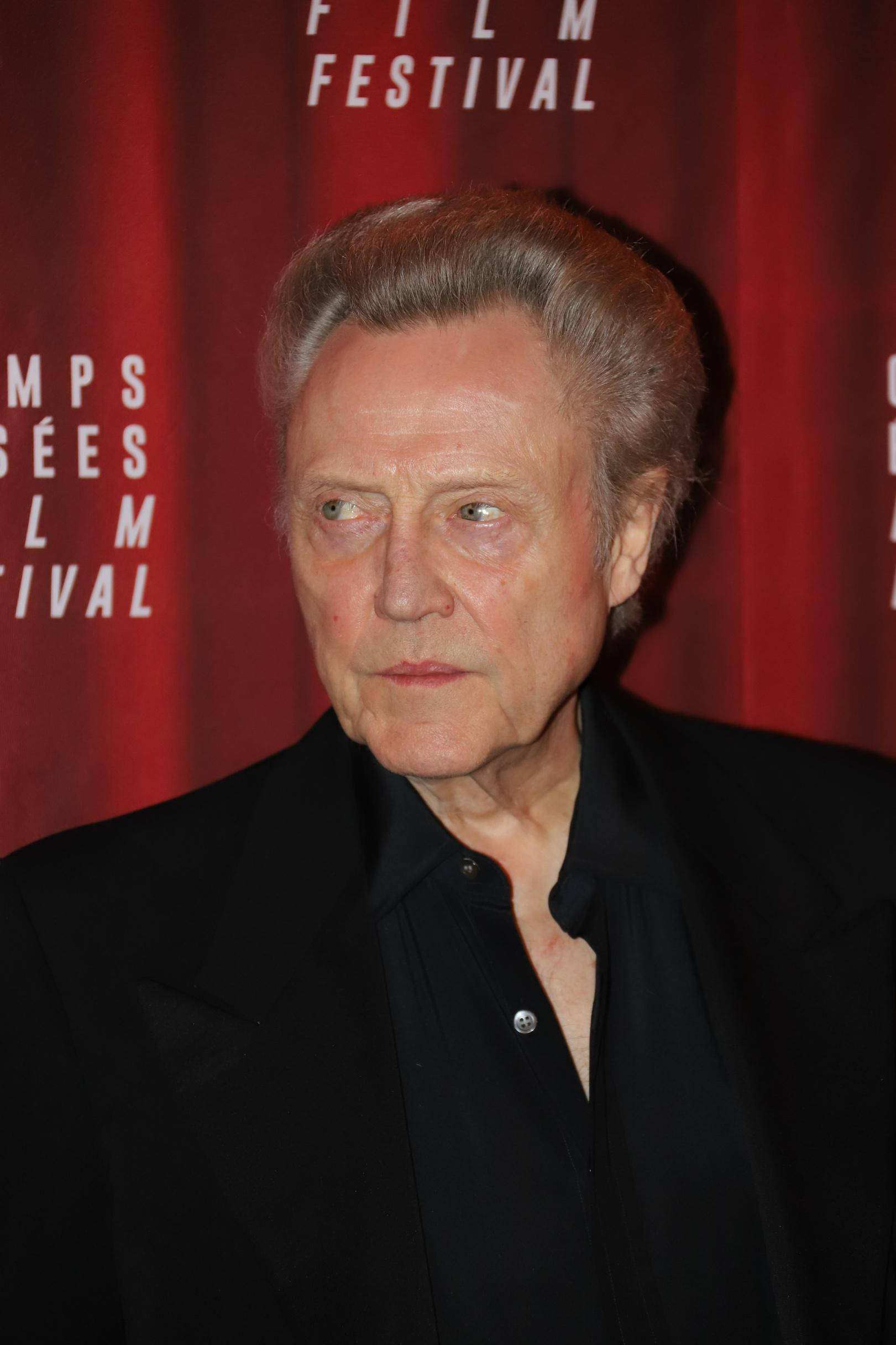 Celebrity 桌布 壁紙 — 一位灰髮年長男士，目光銳利，站在紅色帷幕背景前，上面有白色文字。