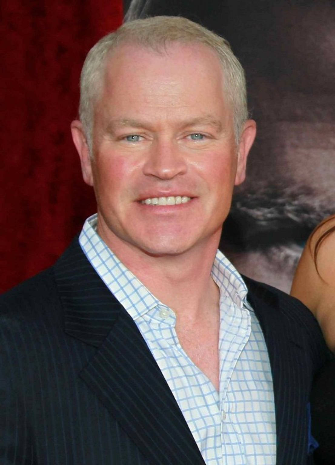 actor 桌布 壁紙 — 一位灰髮微笑男士身穿細條紋西裝，內搭格紋襯衫，背景為紅色。