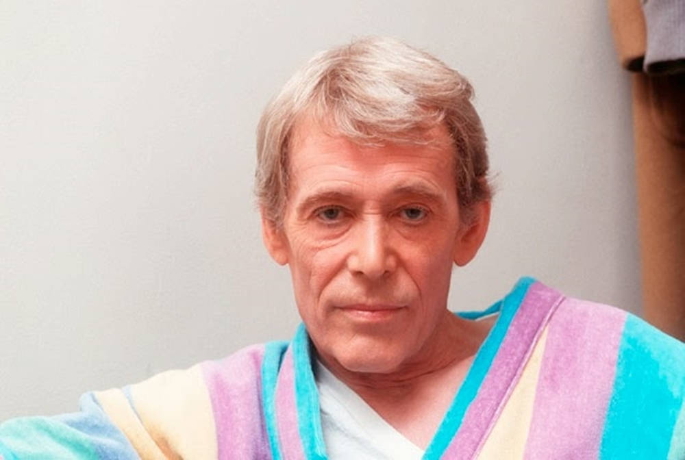 actor 桌布 壁紙 — 一位灰髮男子穿著色彩繽紛的條紋長袍，直視鏡頭，表情中性。