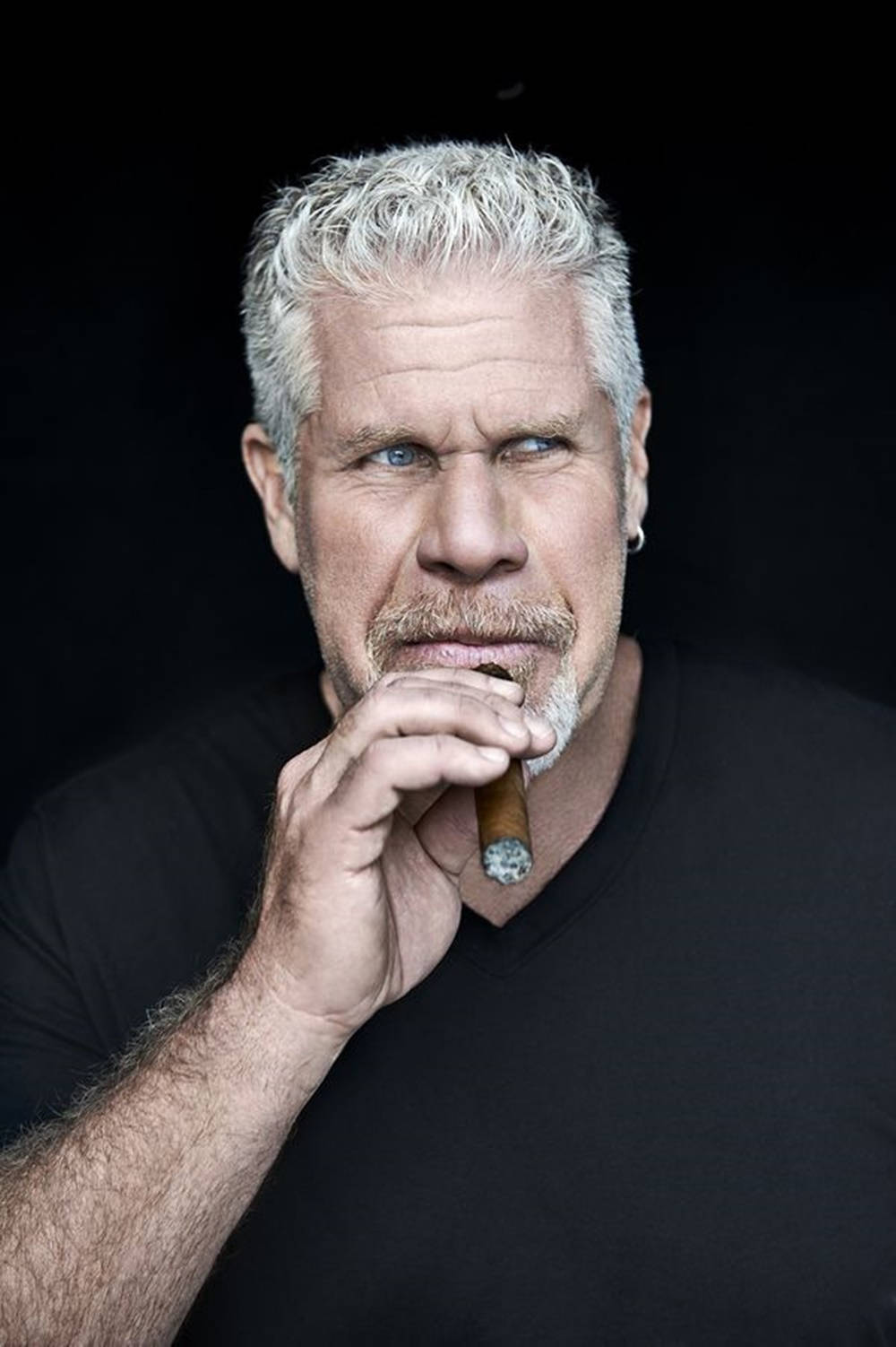 Celebrity 桌布 壁紙 — 一位灰髮藍眼的粗獷男子，在黑色背景前拿著雪茄。