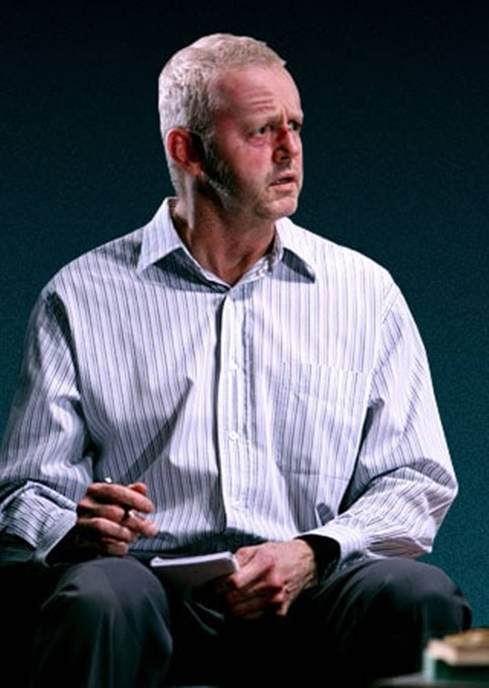 actor 桌布 壁紙 — 一位灰髮鬍鬚男士在昏暗環境中穿著條紋襯衫，手持記事本和筆。