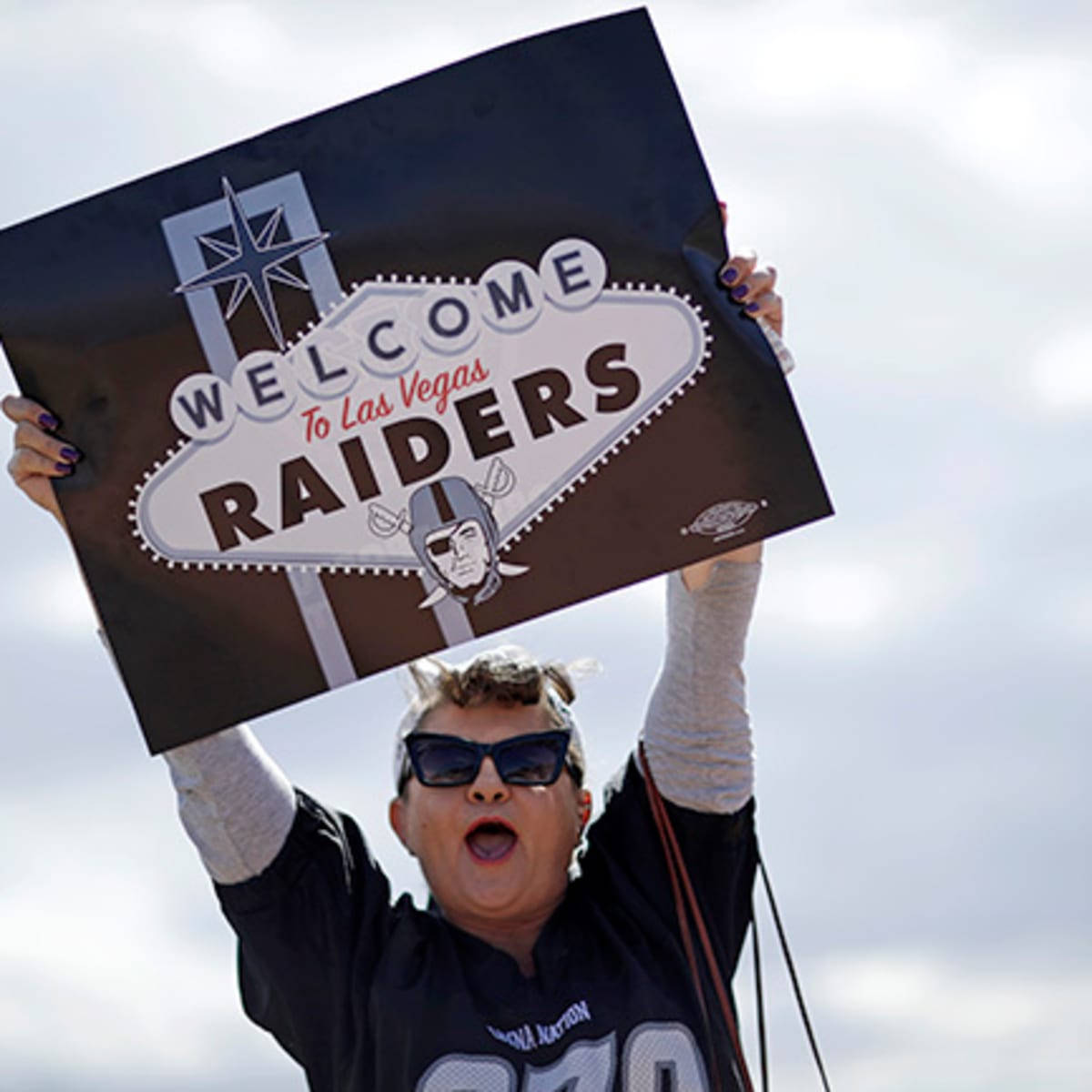 運動 桌布 壁紙 — 一位熱情的粉絲在陰天高舉一個大型 Raiders 歡迎標誌。