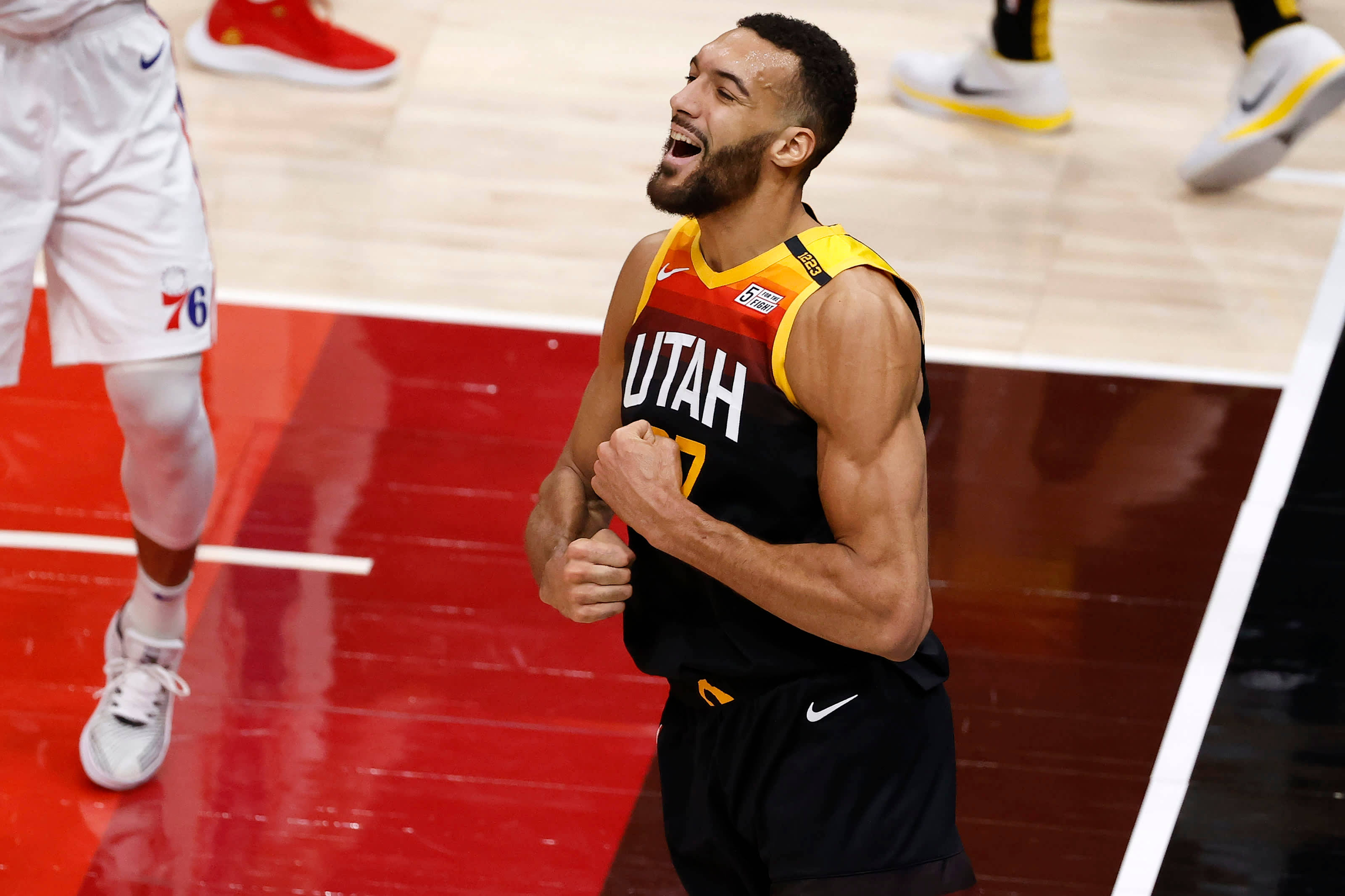 Rudy 桌布 壁紙 — 一位猶他爵士籃球運動員在充滿活力的紅色球場上以勝利的呼喊和緊握的拳頭慶祝。