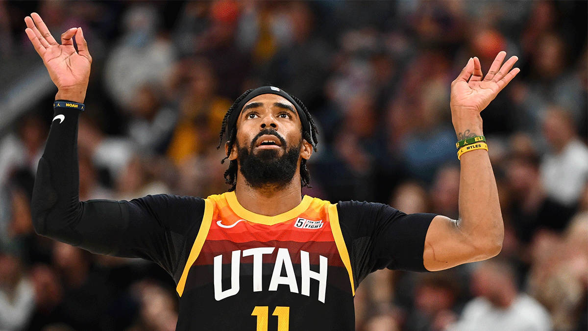 mike conley 桌布 壁紙 — 一位猶他爵士籃球運動員穿著黑色和黃色球衣，在比賽中沮喪地舉起雙手，身後是模糊的人群。