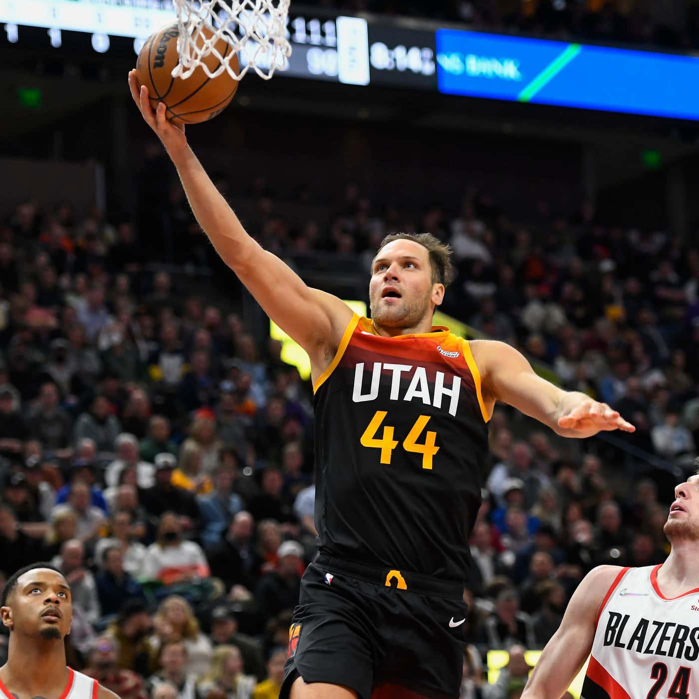 NBA 桌布 壁紙 — 一位猶他爵士隊球員身穿黑橙色球衣，在座無虛席的球場比賽中專注地灌籃。